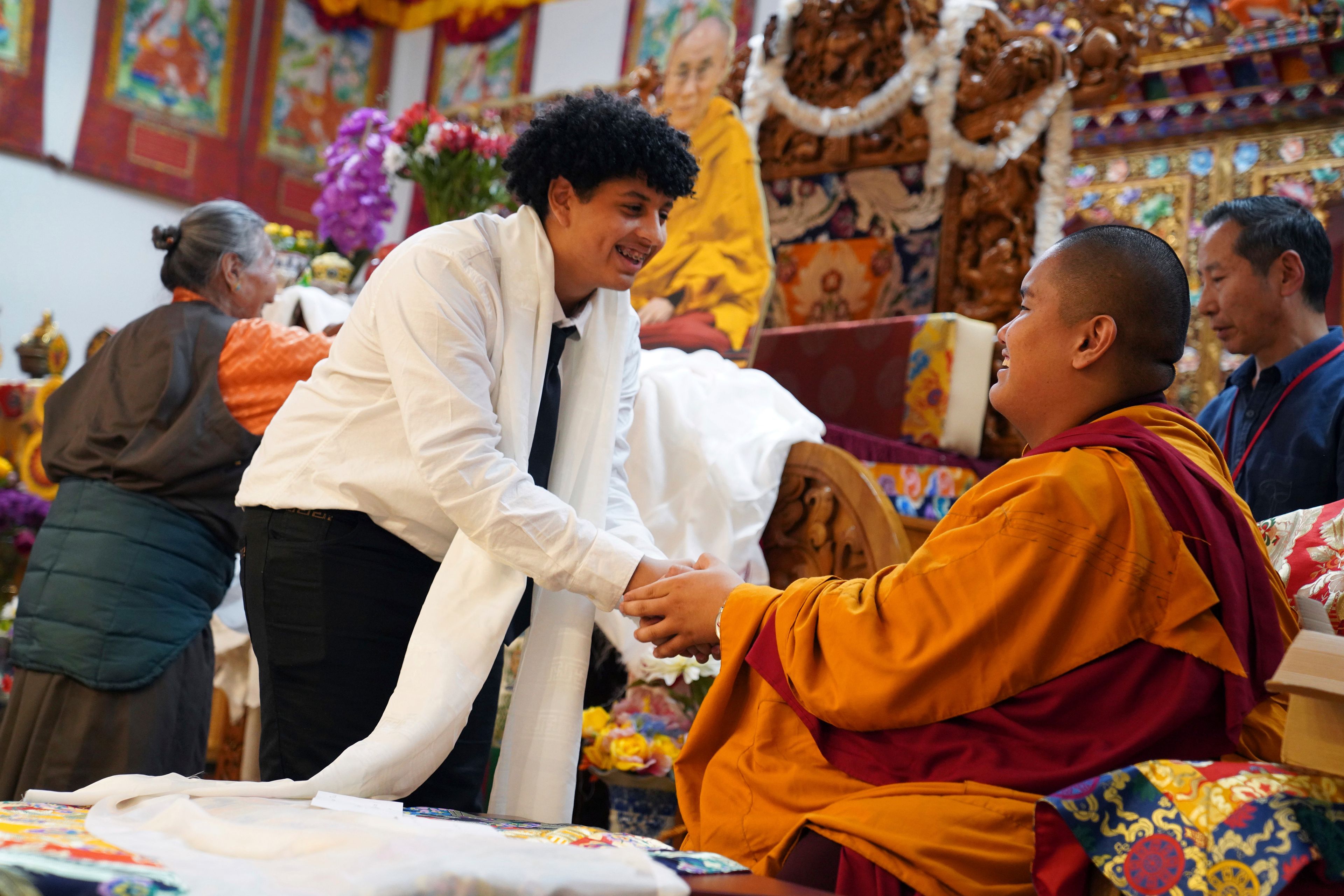 High school friends present U.S.-born Buddhist lama, Jalue Dorje, with a “khata,” the Tibetan ceremonial scarves that symbolize auspiciousness, at his 18th birthday and enthronement ceremony, in Isanti, Minn., on Saturday, Nov. 9, 2024. (AP Photo/Jessie Wardarski)