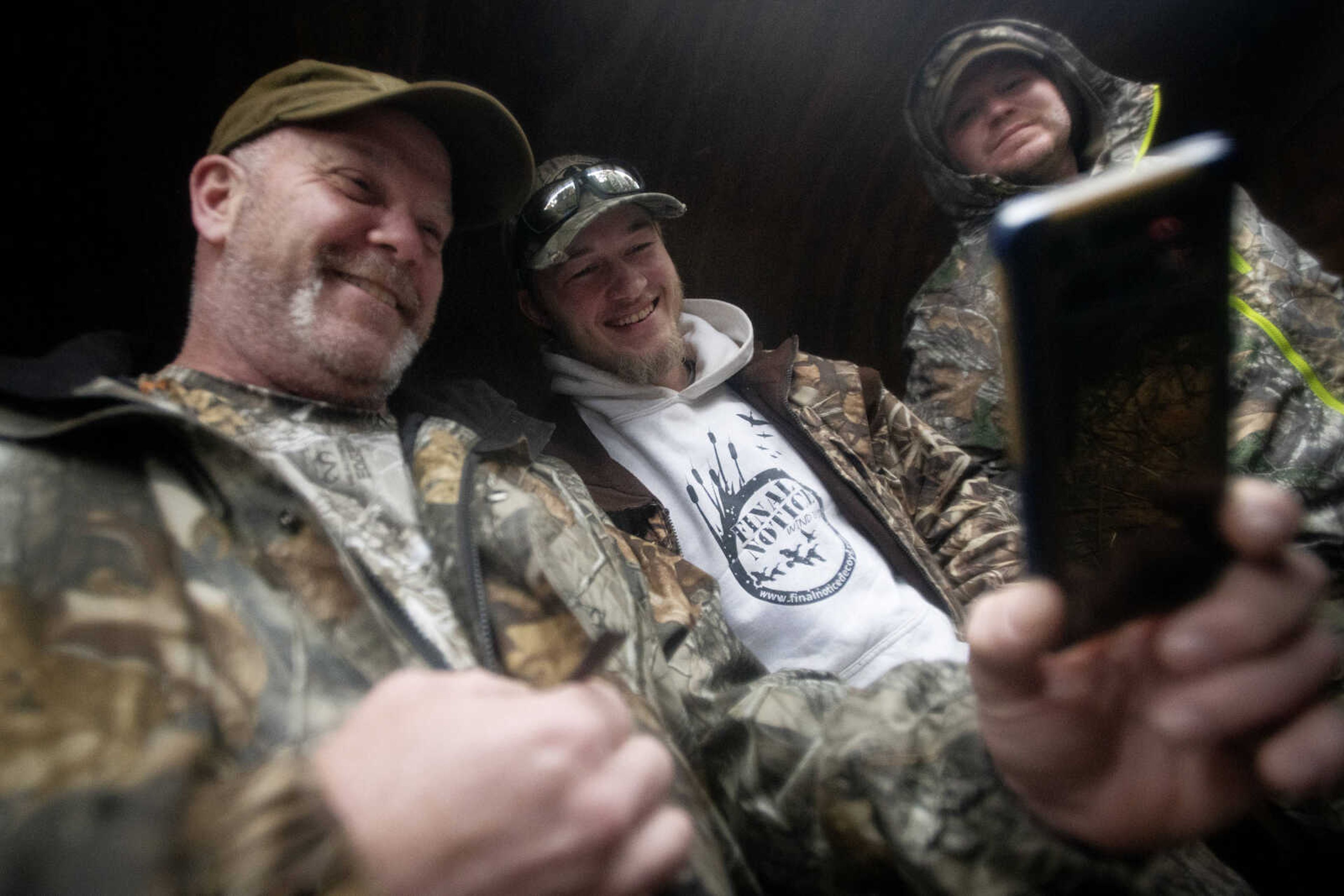 From left: Army veteran Paul Jubinville; Garrett Metje, originally of Cape Girardeau, and now Scott City, Missouri; and active duty Air Force member David Fritz gather around a phone during a snow geese hunt with AM Vets Outdoors on Saturday, March 14, 2020, in Ware, Illinois.