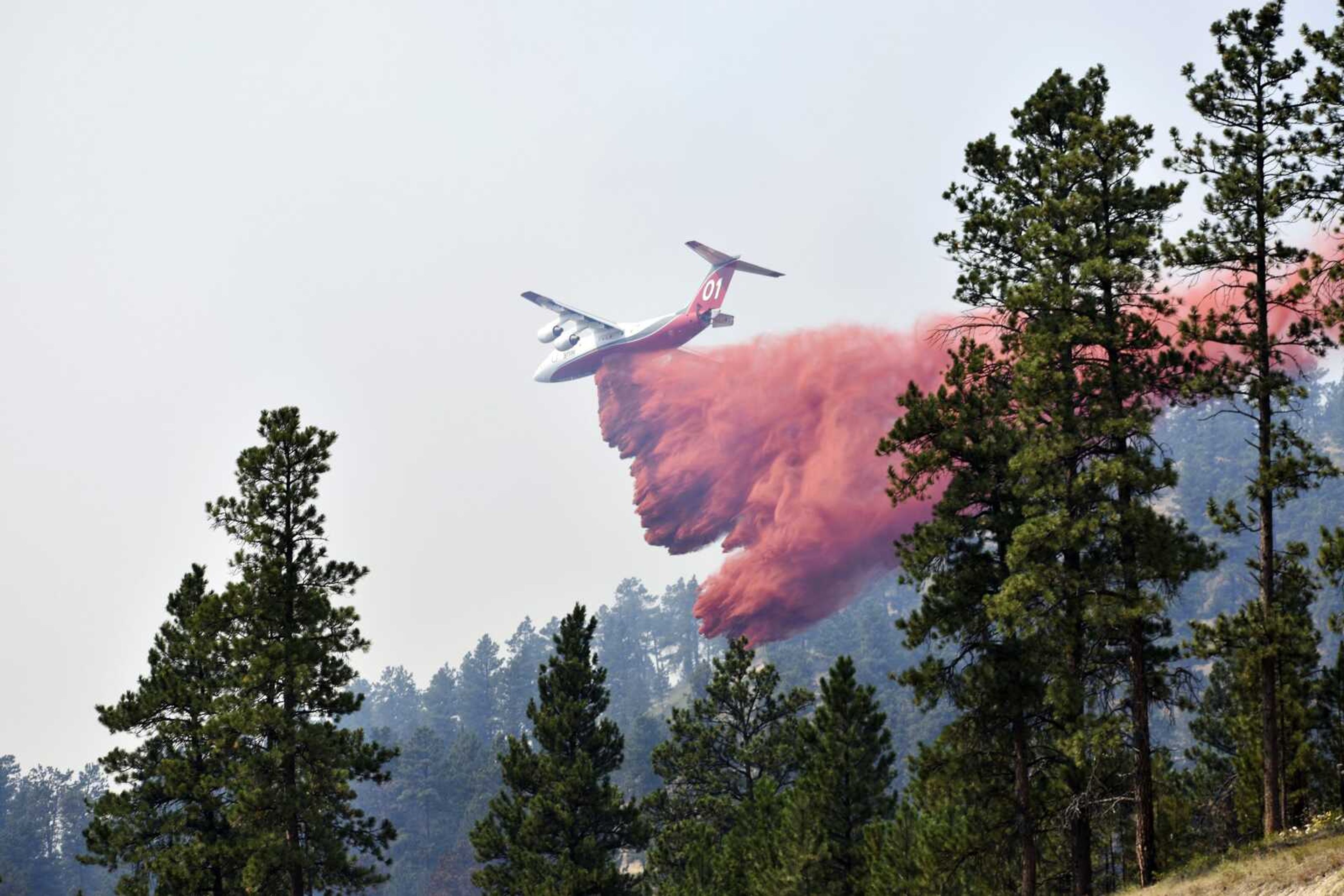 An aircraft drops fire retardant to slow the spread of the Richard Spring fire Wednesday east of Lame Deer, Montana. The fire spread quickly Wednesday as strong winds pushed the flames across rough, forested terrain.