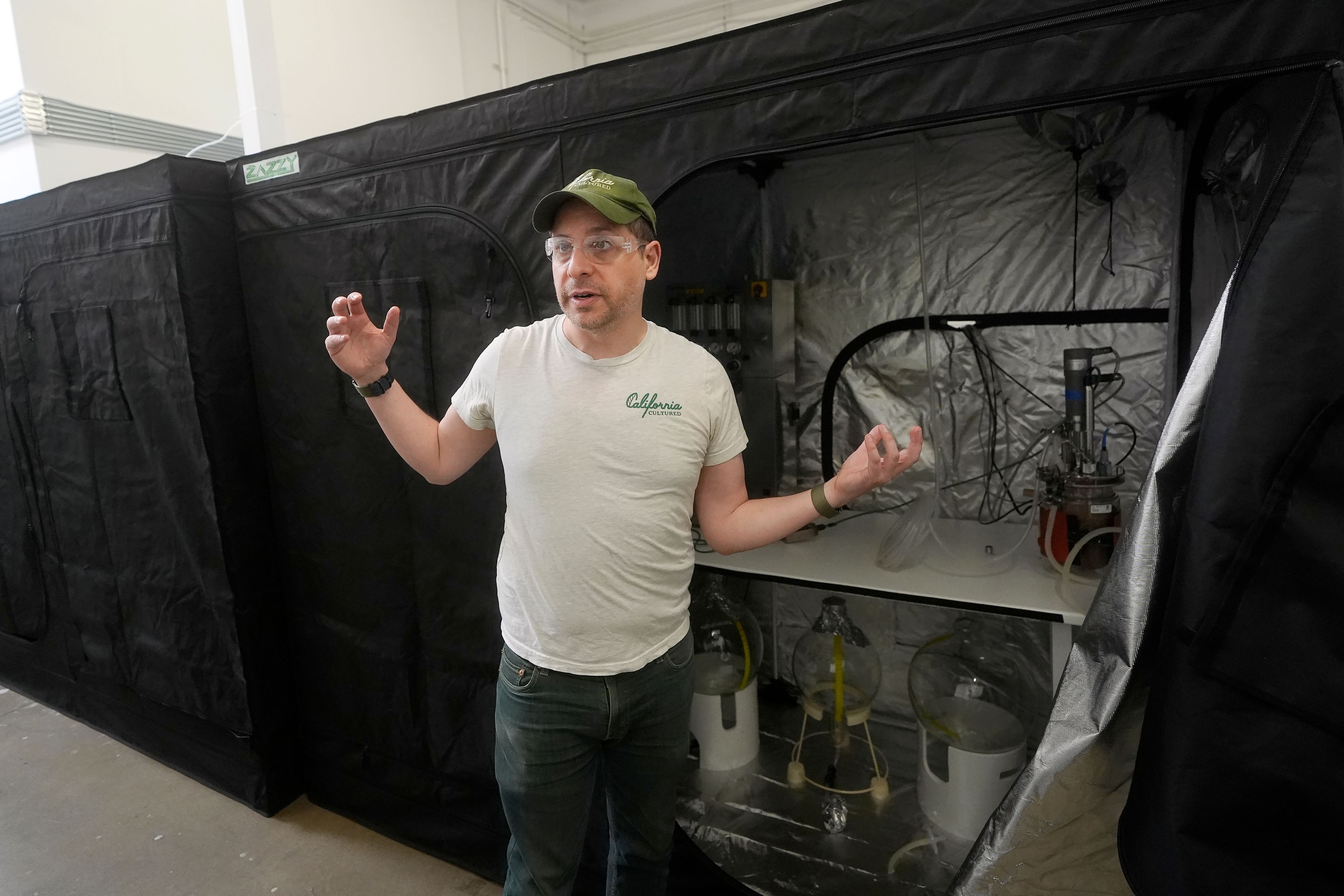 Alan Perlstein, chief executive officer of California Cultured, stands in front of a two-liter bioreactor while being interviewed at the company's lab in West Sacramento, Calif., Wednesday, Aug. 28, 2024. (AP Photo/Jeff Chiu)