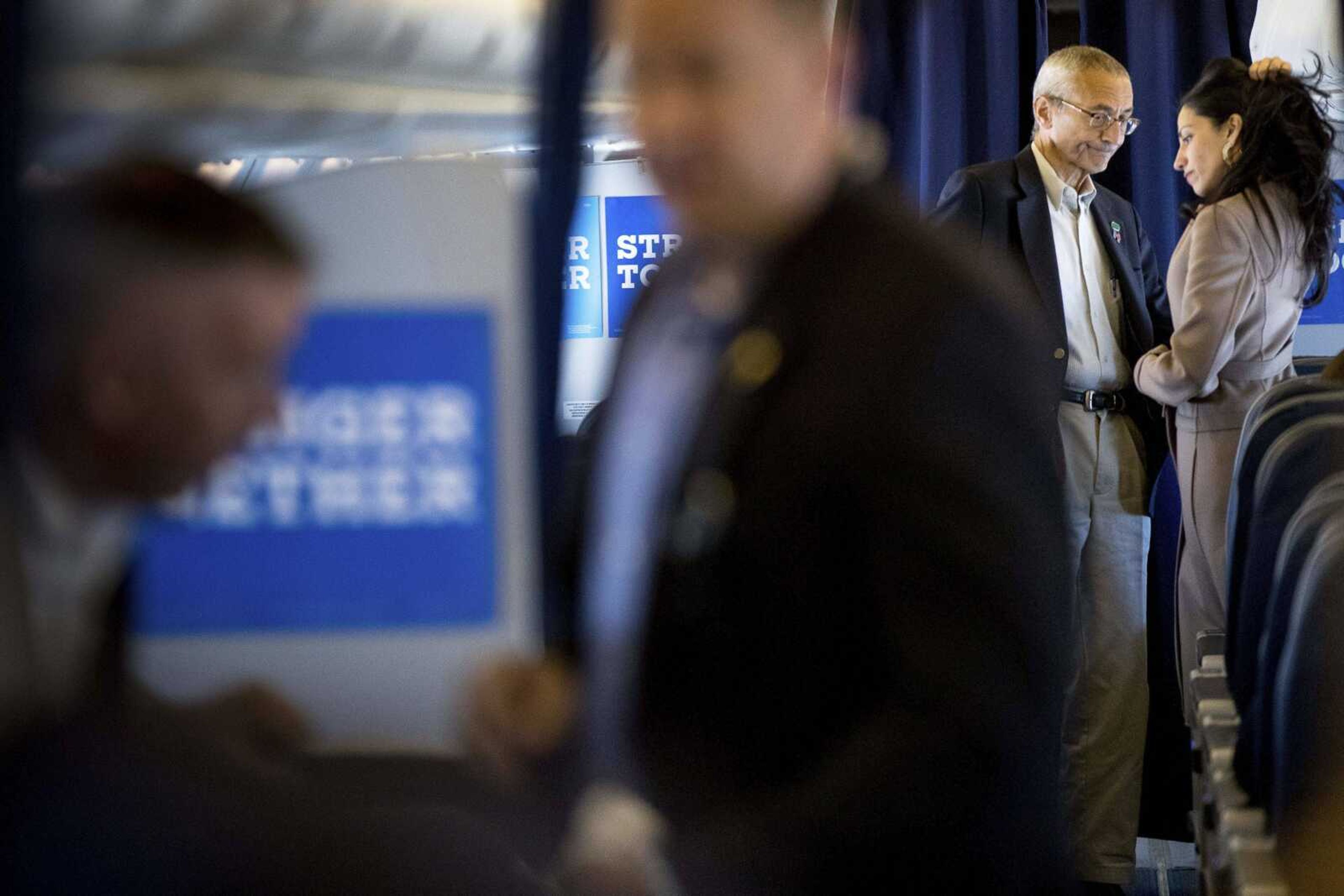 Hillary Clinton's campaign manager John Podesta, second from right, pauses while speaking with senior aide Huma Abedin aboard Clinton's campaign plane while traveling Tuesday to Miami for a rally.