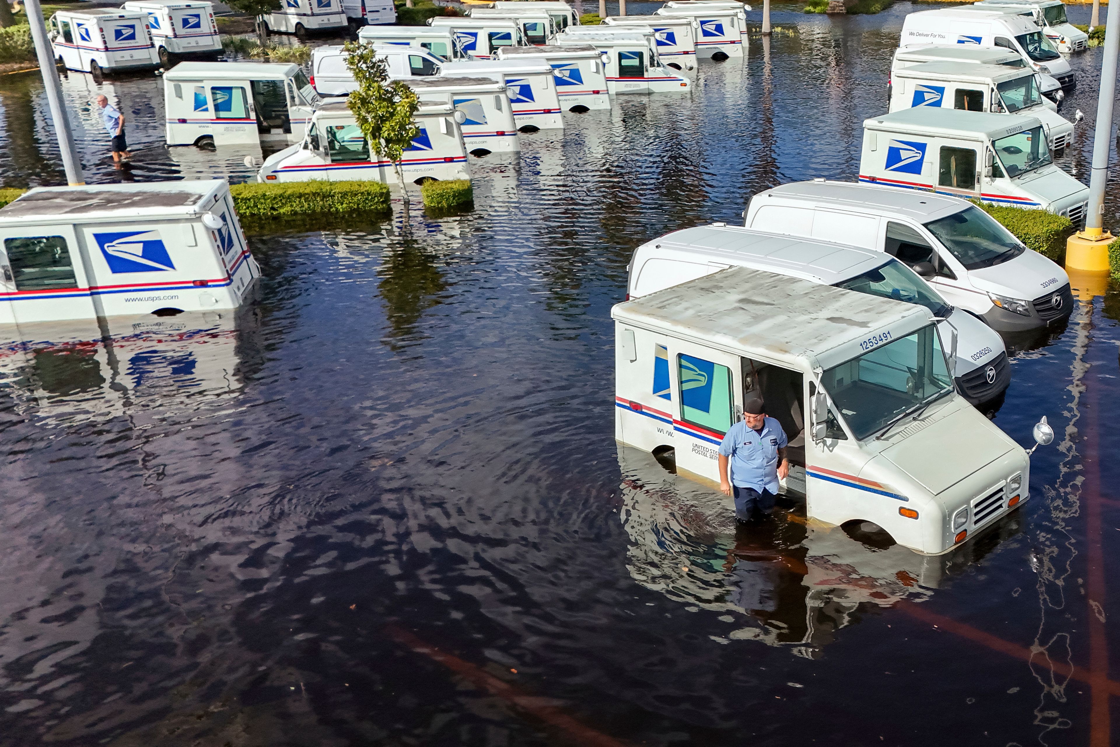 A USPS worker inspects trucks that had been relocated to protect them from wind but which are now underwater as intense rain from Hurricane Milton caused the Anclote River to flood, Friday, Oct. 11, 2024, in New Port Richey, Fla. (AP Photo/Mike Carlson)