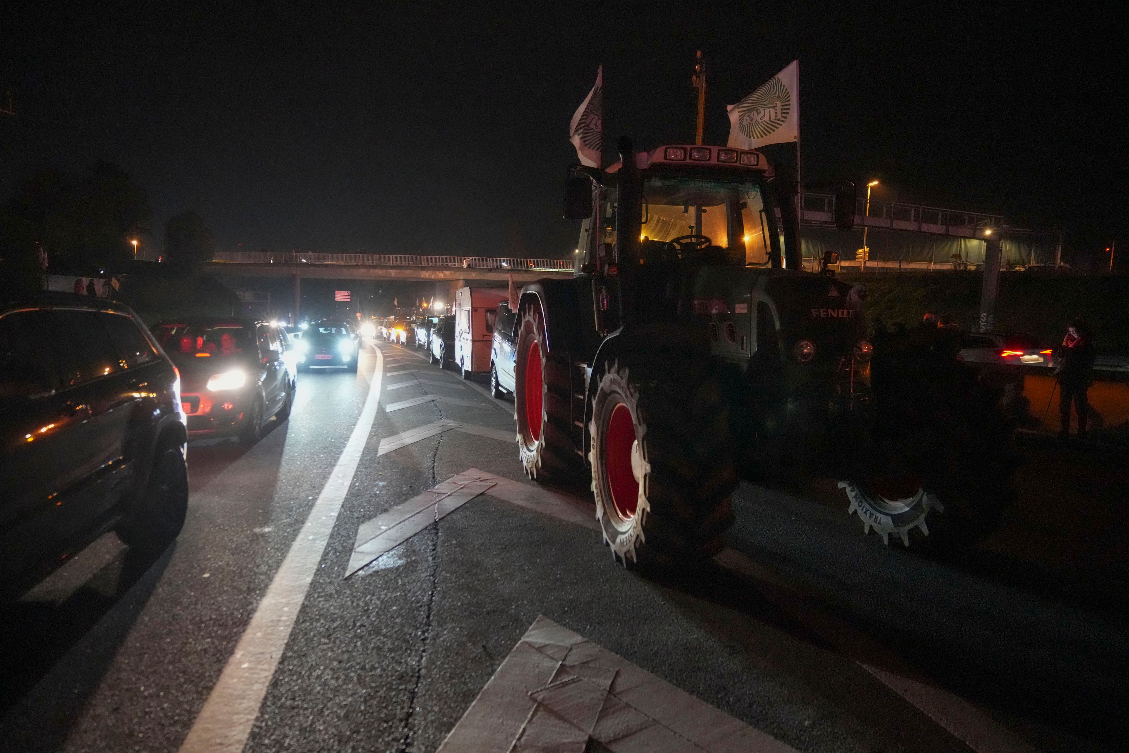 Cars drive along tractors on a blocked highway in Velizy-Villacoublay, outside Paris, Sunday, Nov. 17, 2024. (AP Photo/Michel Euler)