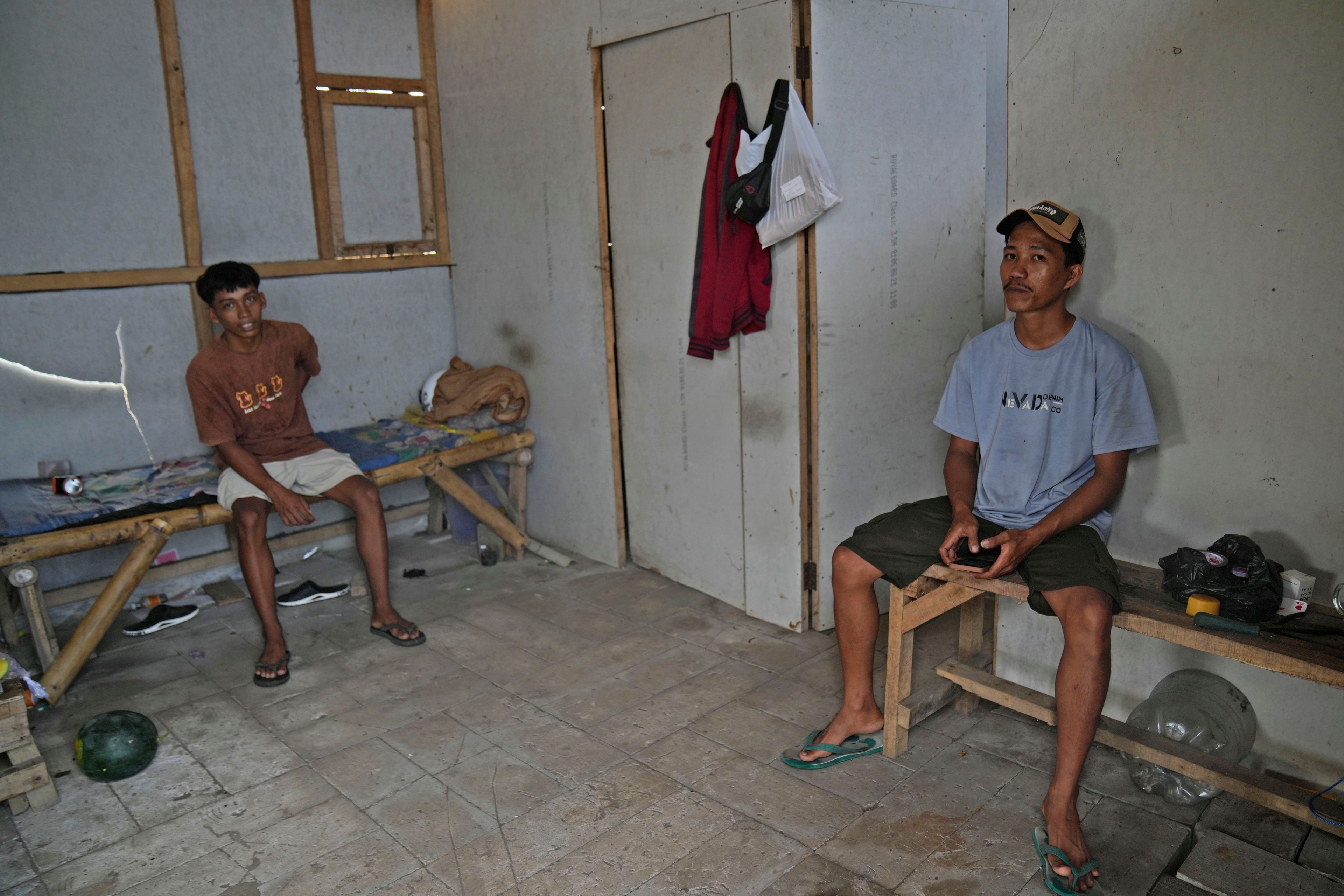 Andika Yudha Agusta, right, and his brother Dias Yudho Prihantoro who work together at a shrimp farm sit inside the hut where they stay during their work shifts at the farm in Kebumen, Central Java, Indonesia, Tuesday, Sept. 24, 2024. (AP Photo/Dita Alangkara)