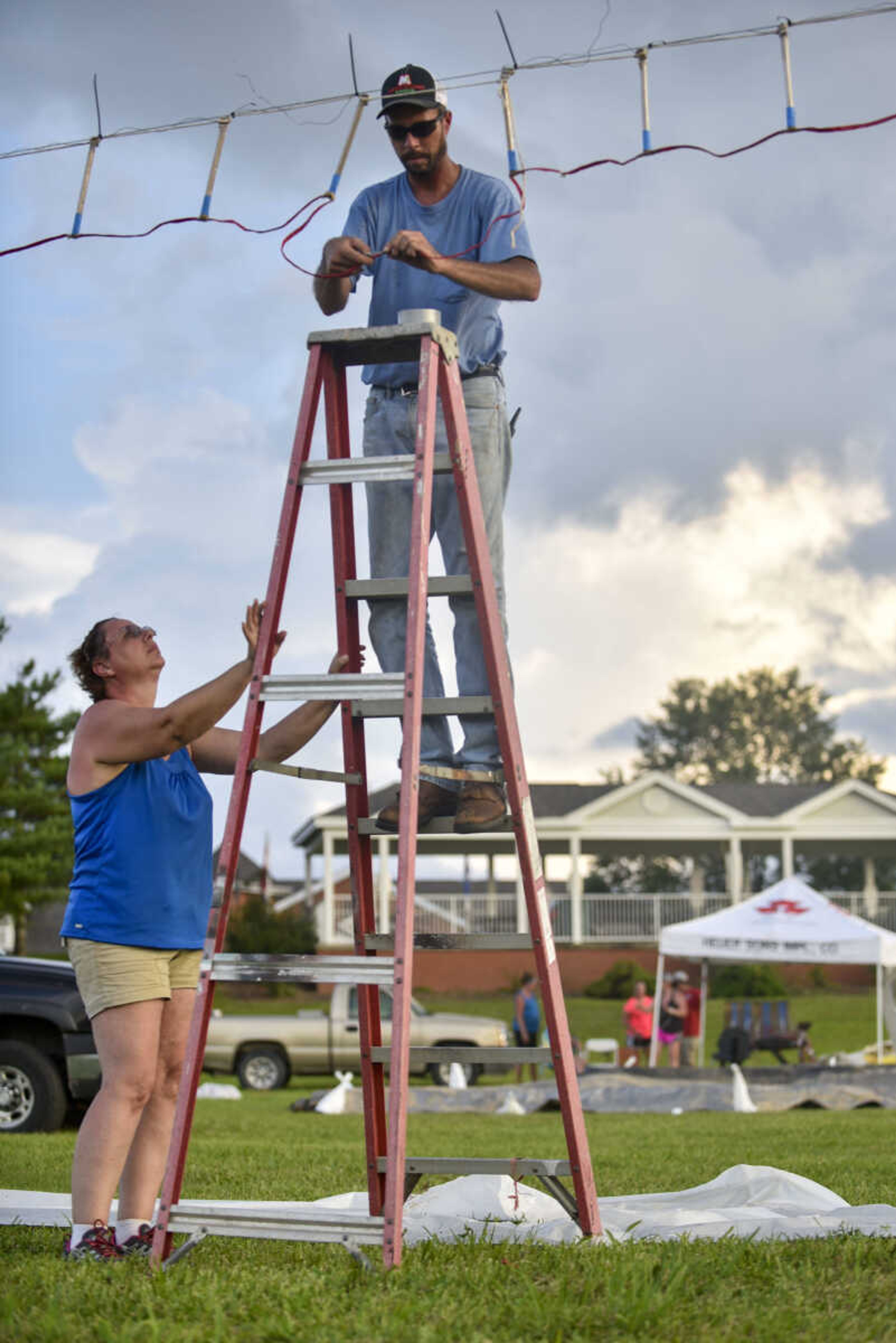 Fireworks show producer Tony Tucker, center, of McClure, Illinois, wires a strand of waterfalls with help from his fiance, Jenny Hawkins, as night falls Tuesday, July 3, 2018, at the Missouri Veterans Home in Cape Girardeau.