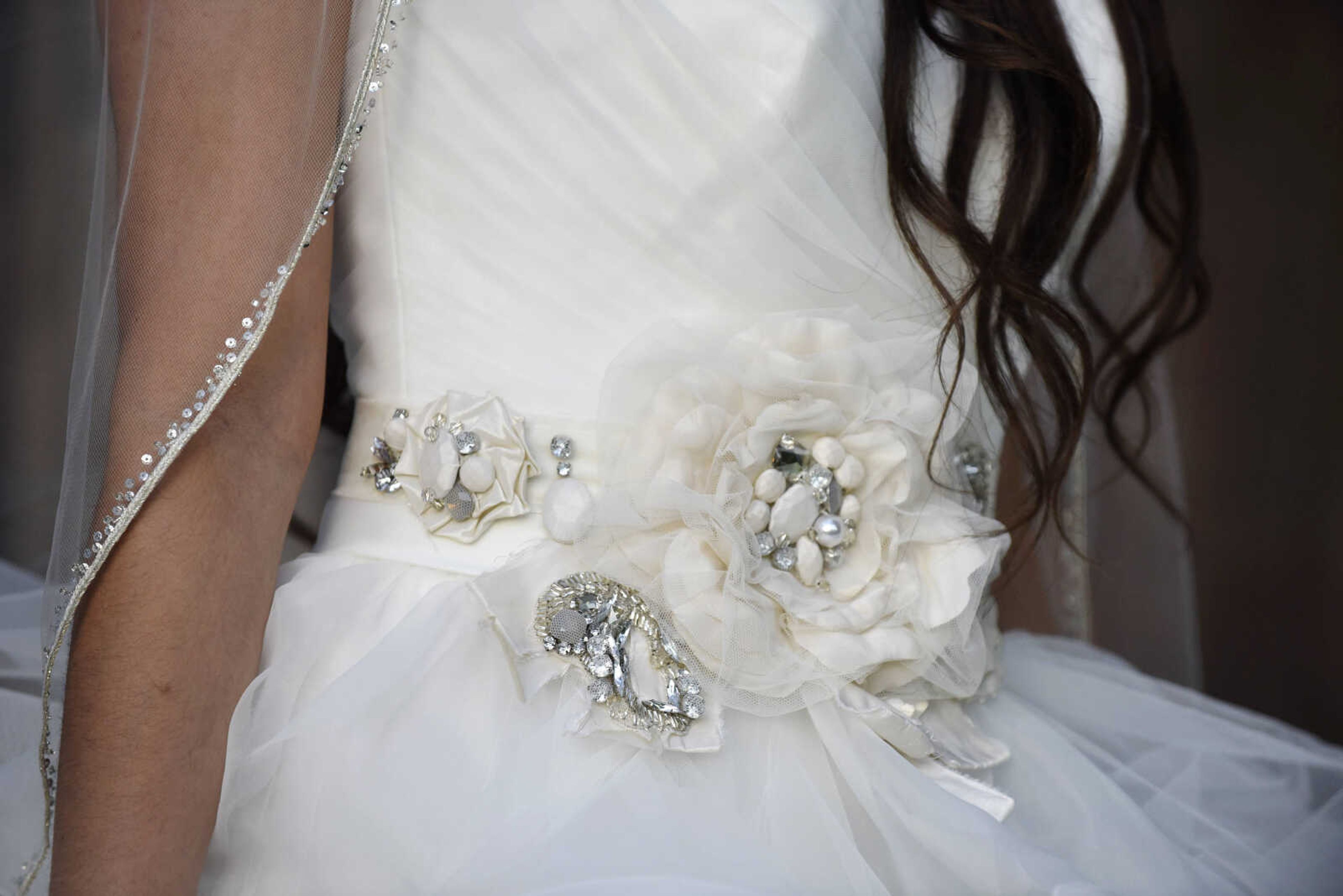 Allure Bridals strapless horsehair gown with flower belt from Enzoani, veil from Giselle Bridal and Jim Ball earrings. Available at Joy's Bridal in Sikeston, Missouri.