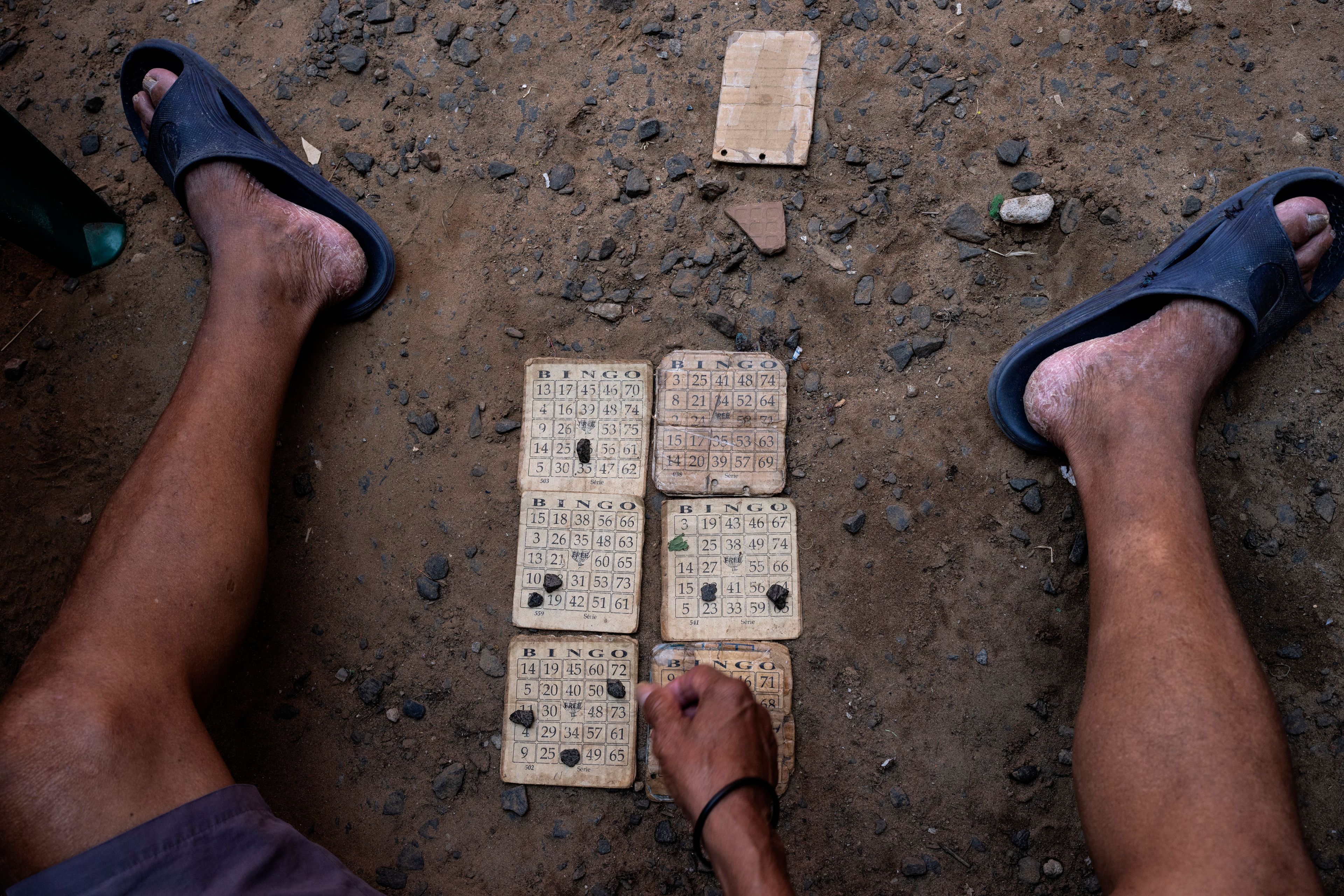 A prisoner uses pebbles to mark his bingo card in the prison yard of the Regional Penitentiary in Villarica, Paraguay, Friday, Aug. 30, 2024. Prisoners pay per bingo card and the winner takes all. (AP Photo/Rodrigo Abd)