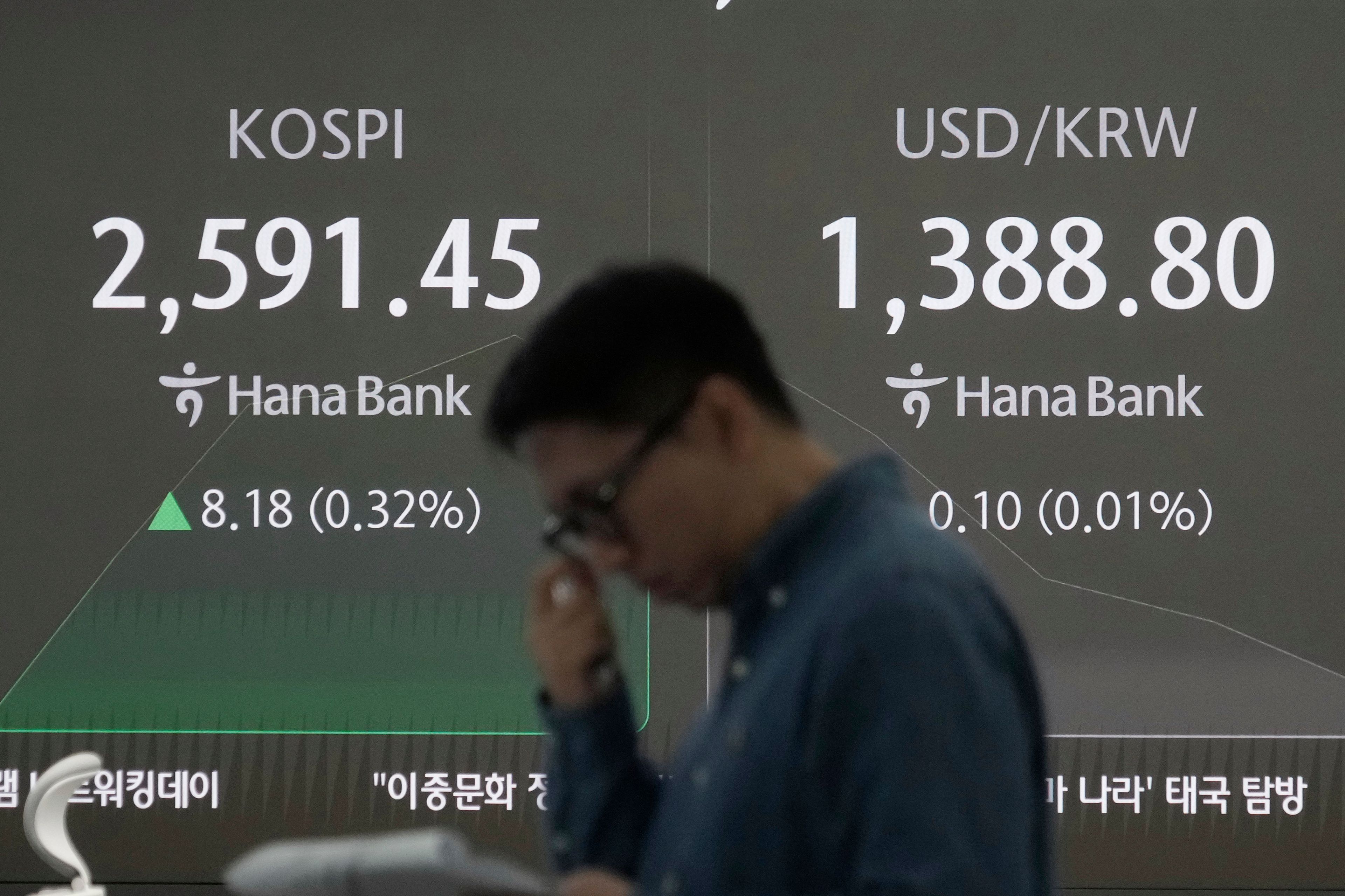 A currency trader works near a screen showing the Korea Composite Stock Price Index (KOSPI), left, and the foreign exchange rate between U.S. dollar and South Korean won at the foreign exchange dealing room of the KEB Hana Bank headquarters in Seoul, South Korea, Monday, Oct. 28, 2024. (AP Photo/Ahn Young-joon)