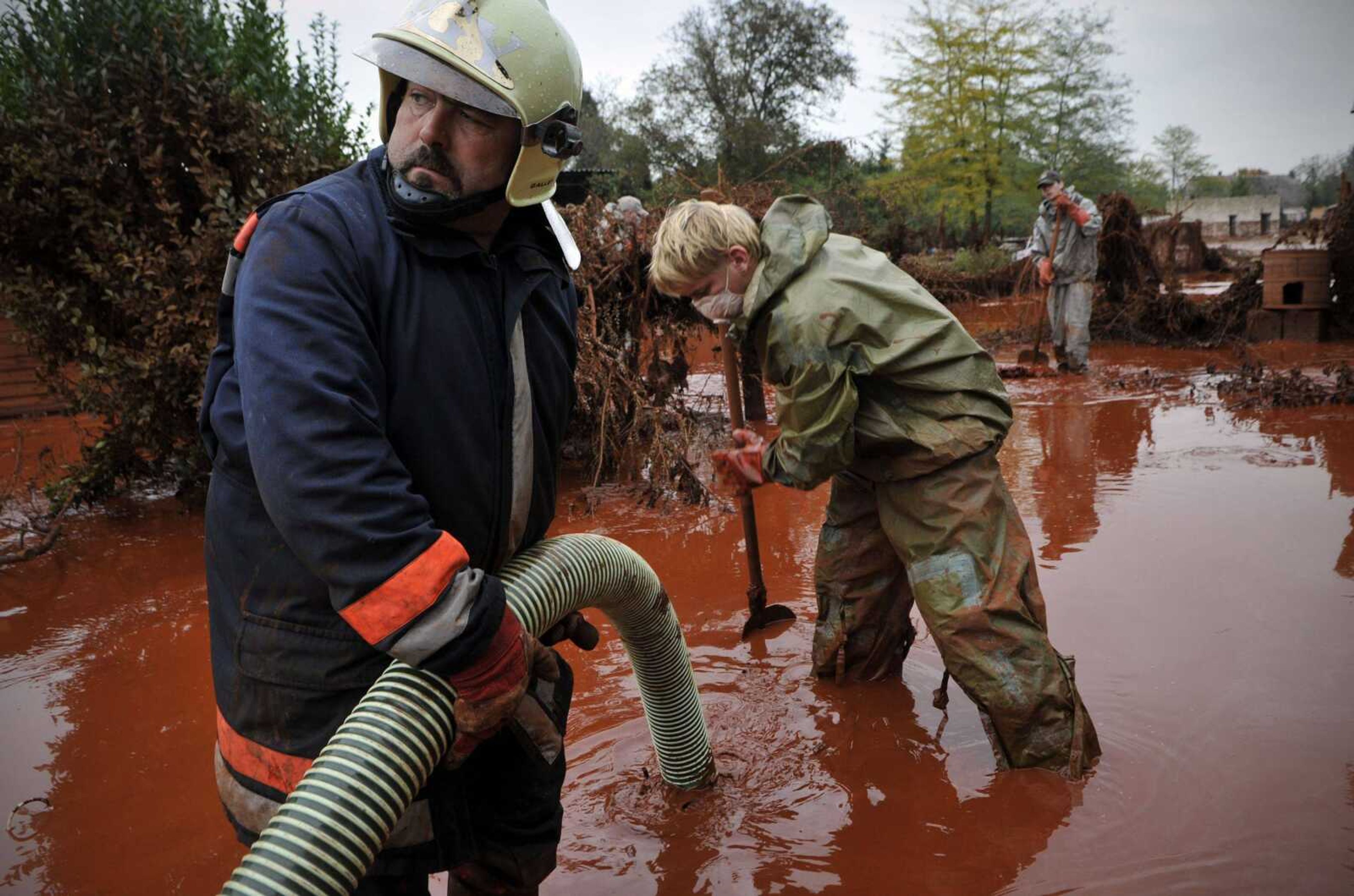 Hungarian firefighters clean a yard flooded by toxic mud in Devecser, Hungary, on Wednesday. The mud reached the Danube on Thursday, Hungarian authorities said. (Bela Szandelszky ~ Associated Press)