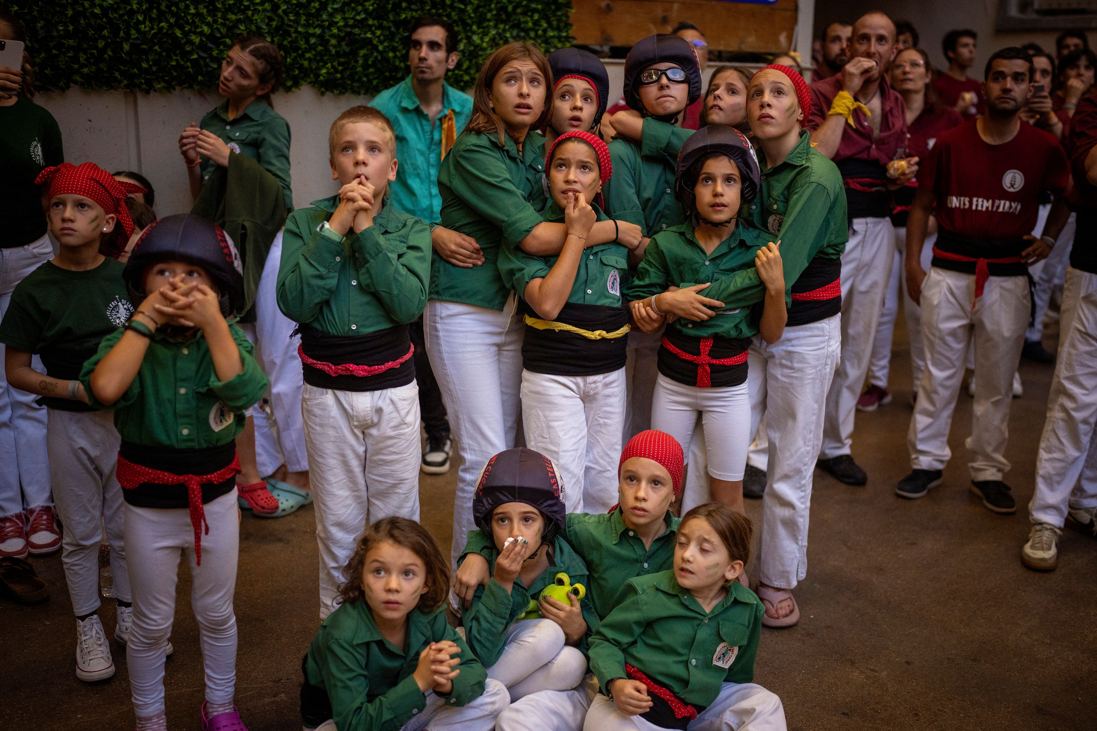 Assistants look as members of "Castellers Jove de Barcelona" form a "Castell" or human tower, during the 29th Human Tower Competition in Tarragona, Spain, Saturday, Oct. 5, 2024. (AP Photo/Emilio Morenatti)