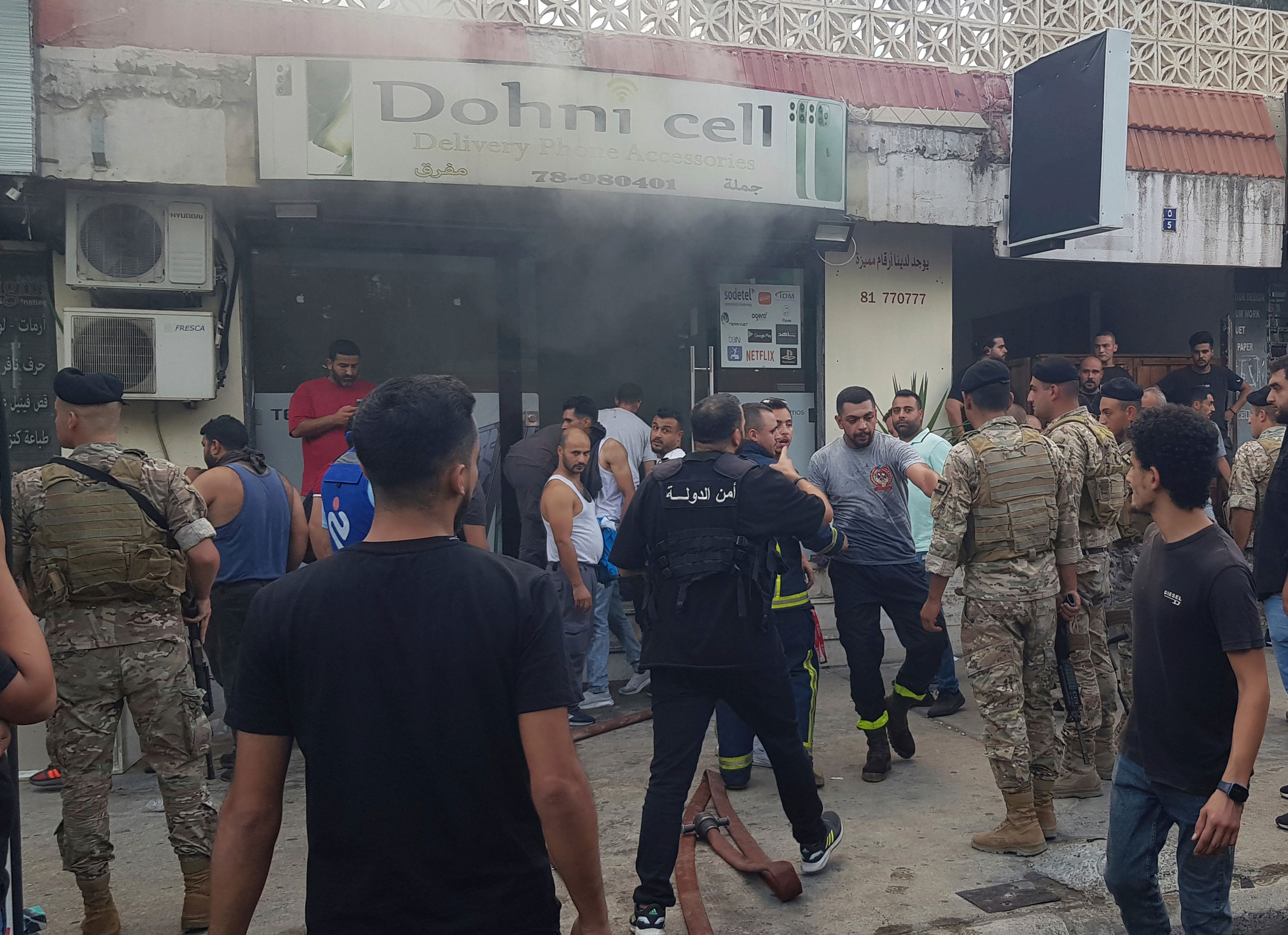 Lebanese soldiers and firefighters gather outside a mobile shop after what is believed to be the result of a walkie-talkie exploding inside it, in the southern port city of Sidon, Lebanon, Wednesday, Sept. 18, 2024. (AP Photo/Mohammed Zaatari)