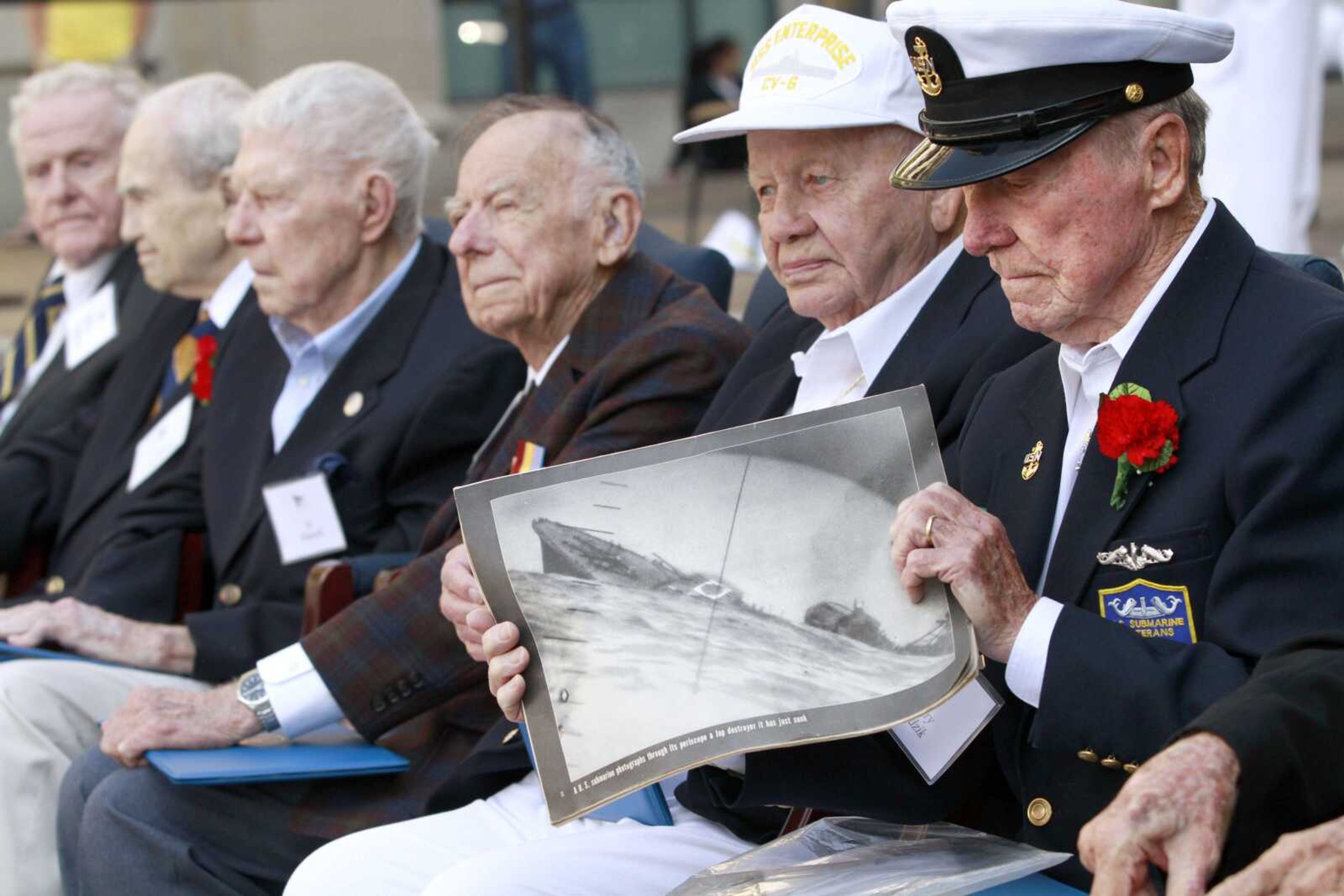 World War II Battle of Midway veteran Henry Kudzik, 87, of Bethlehem, Pa., right, holds a photograph of a sinking destroyer, next to fellow veterans including Howard Snell, of Kingman, Ariz., during a Battle of Midway 70th Commemoration ceremony Monday at the U.S. Navy Memorial in Washington. (Jacquelyn Martin ~ Associated Press)