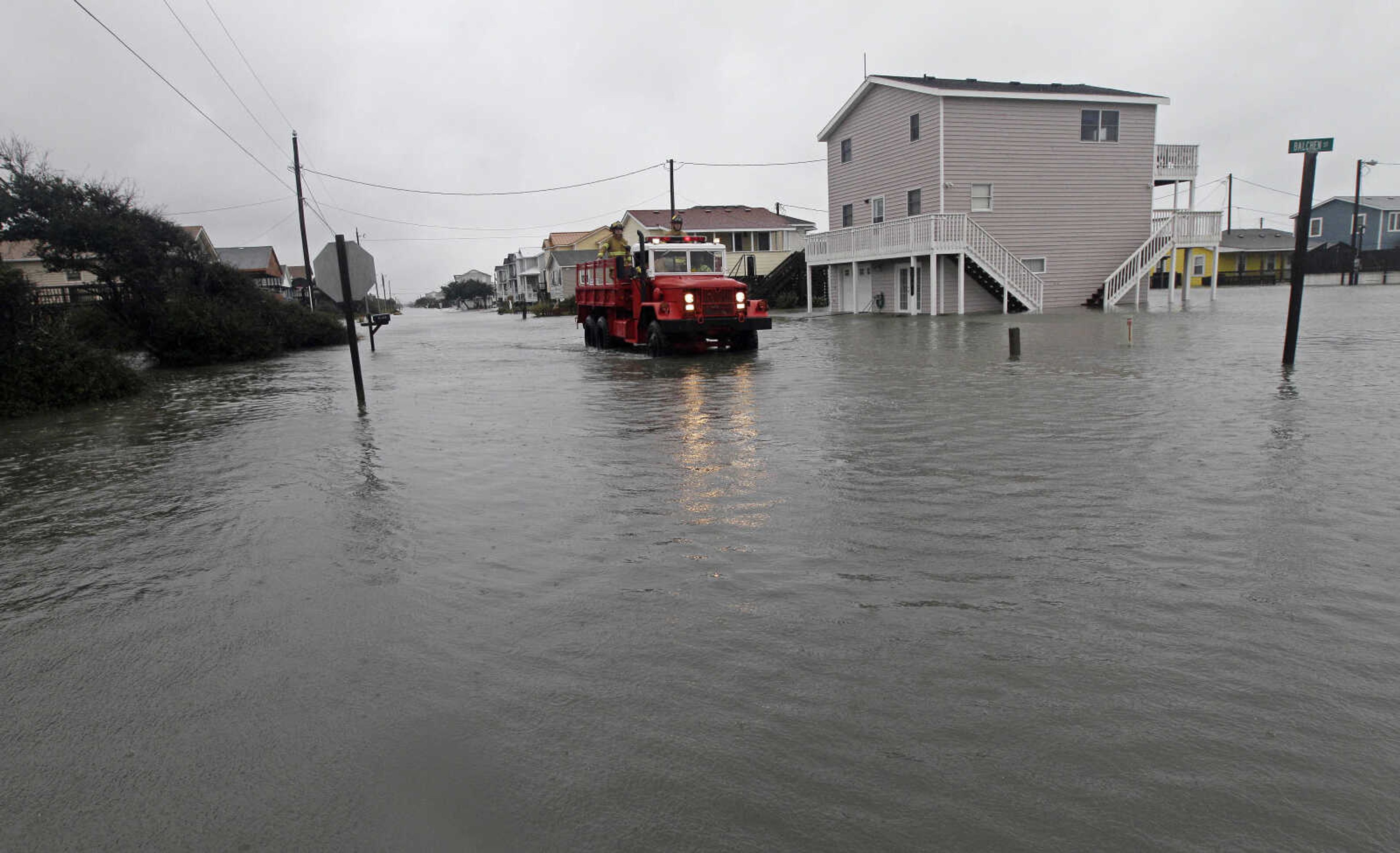 Members of the Kitty Hawk Fire Department patrol along a flooded Ride Lane in Kitty Hawk, N.C., Monday, Oct. 29, 2012 after Hurricane Sandy's wind and rain left many roads impassable. Hurricane Sandy continued on its path Monday, as the storm forced the shutdown of mass transit, schools and financial markets, sending coastal residents fleeing, and threatening a dangerous mix of high winds and soaking rain.  (AP Photo/Gerry Broome)