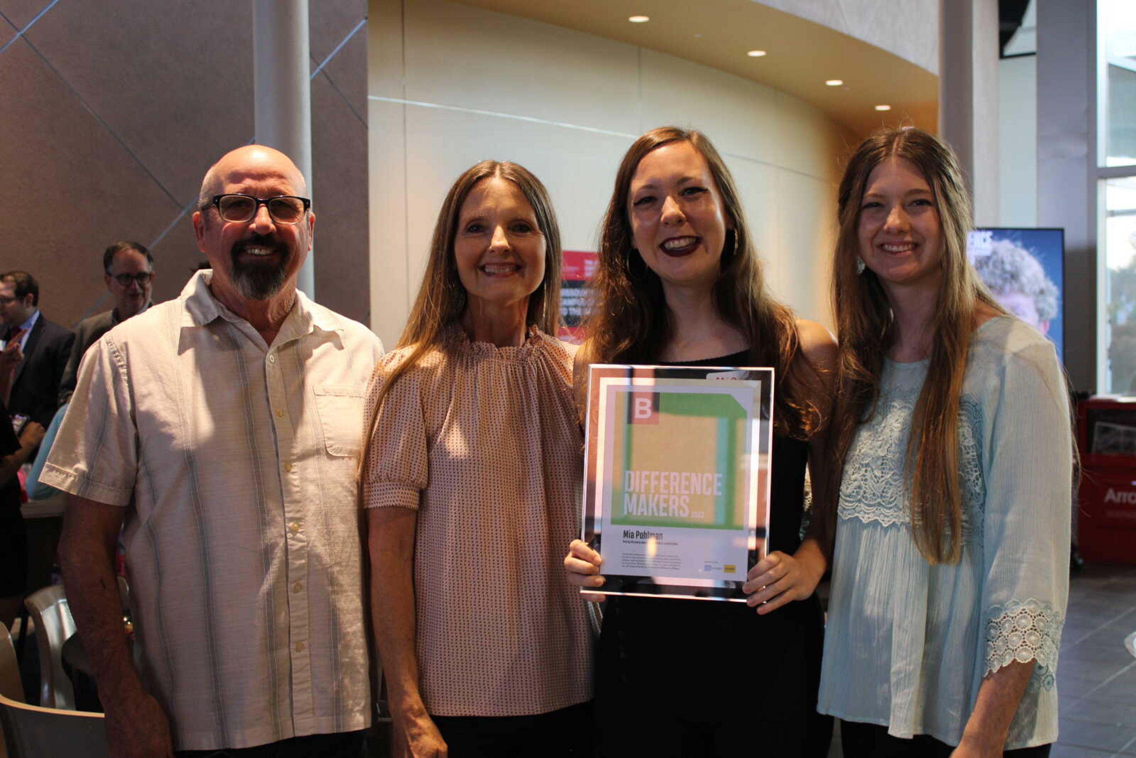 Mia Pohlman takes a photo with family after receiving her Difference Maker award.