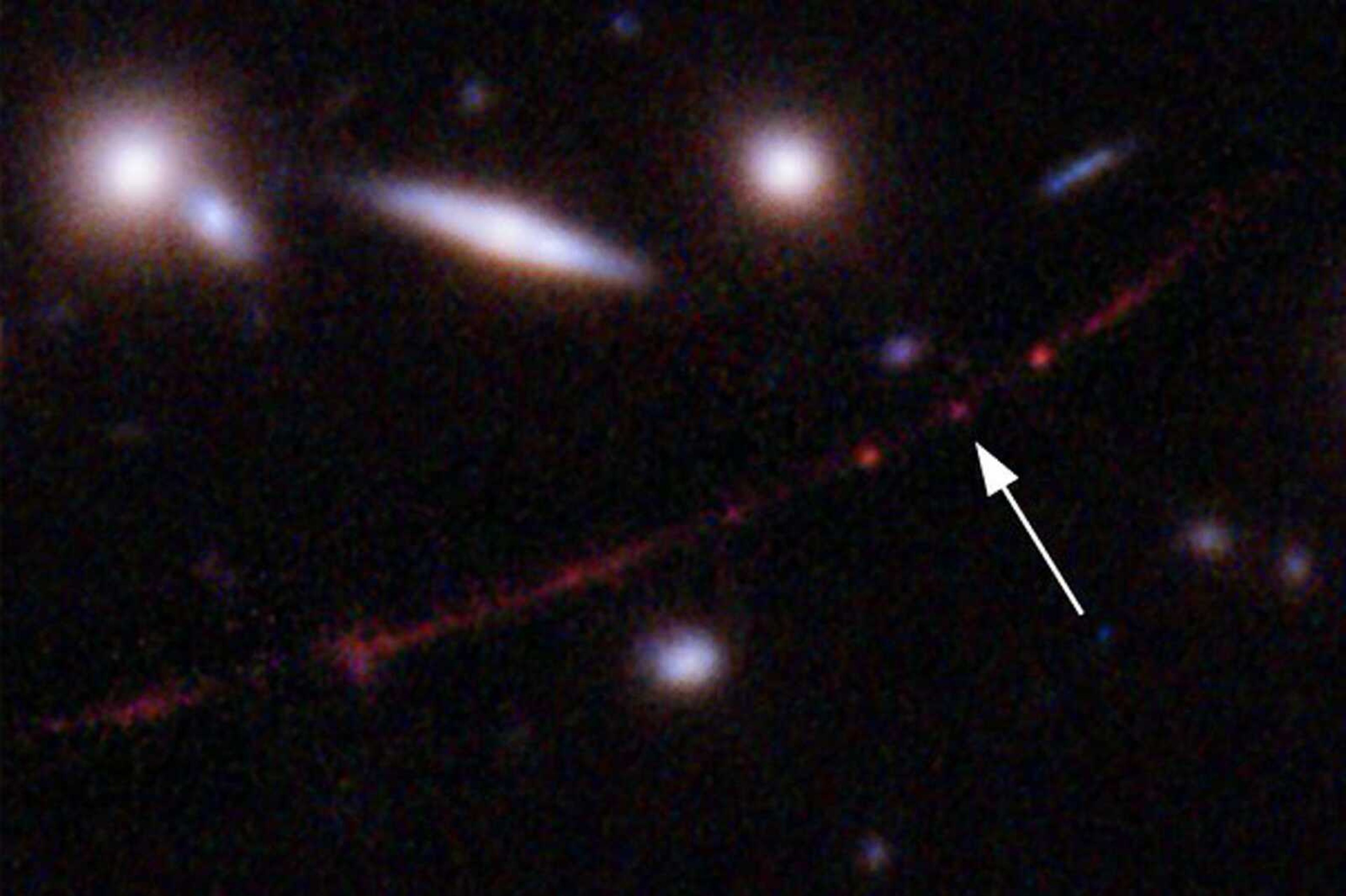 This image made available Wednesday shows the star Earendel, indicated by arrow, and the Sunrise Arc galaxy, stretching from lower left to upper right, optically bent because of a massive galaxy cluster between it and the Hubble Space Telescope, which captured the light. The mass of the galaxy cluster serves as a magnifying glass, allowing Earendel to be seen.