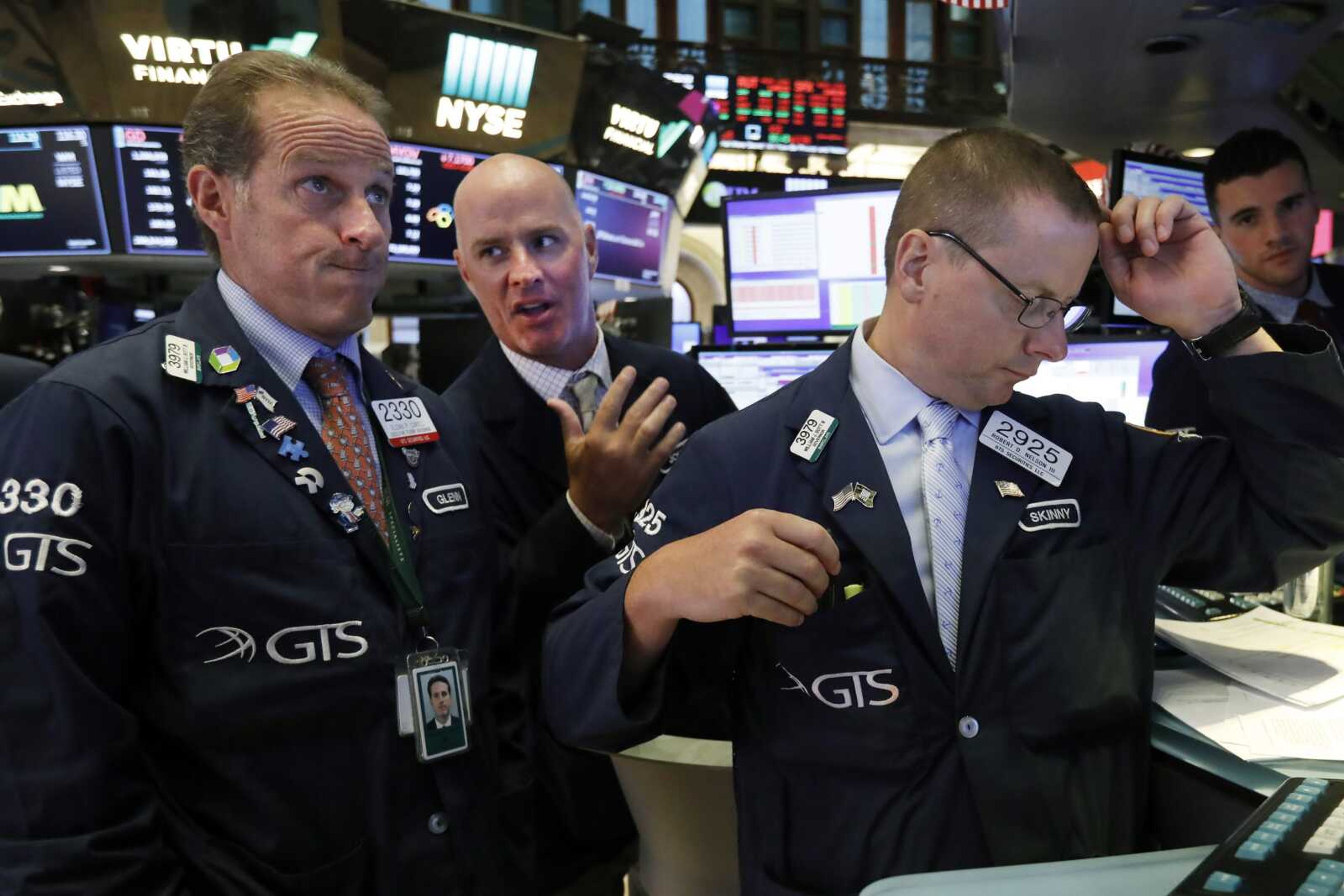 Specialists Glenn Carell, left, John 'Hara, center, and Robert Nelson gather Wednesday at a trading post on the floor of the New York Stock Exchange. The Dow Jones Industrial Average sank 800 points after the bond market flashed a warning sign about a possible recession for the first time since 2007.