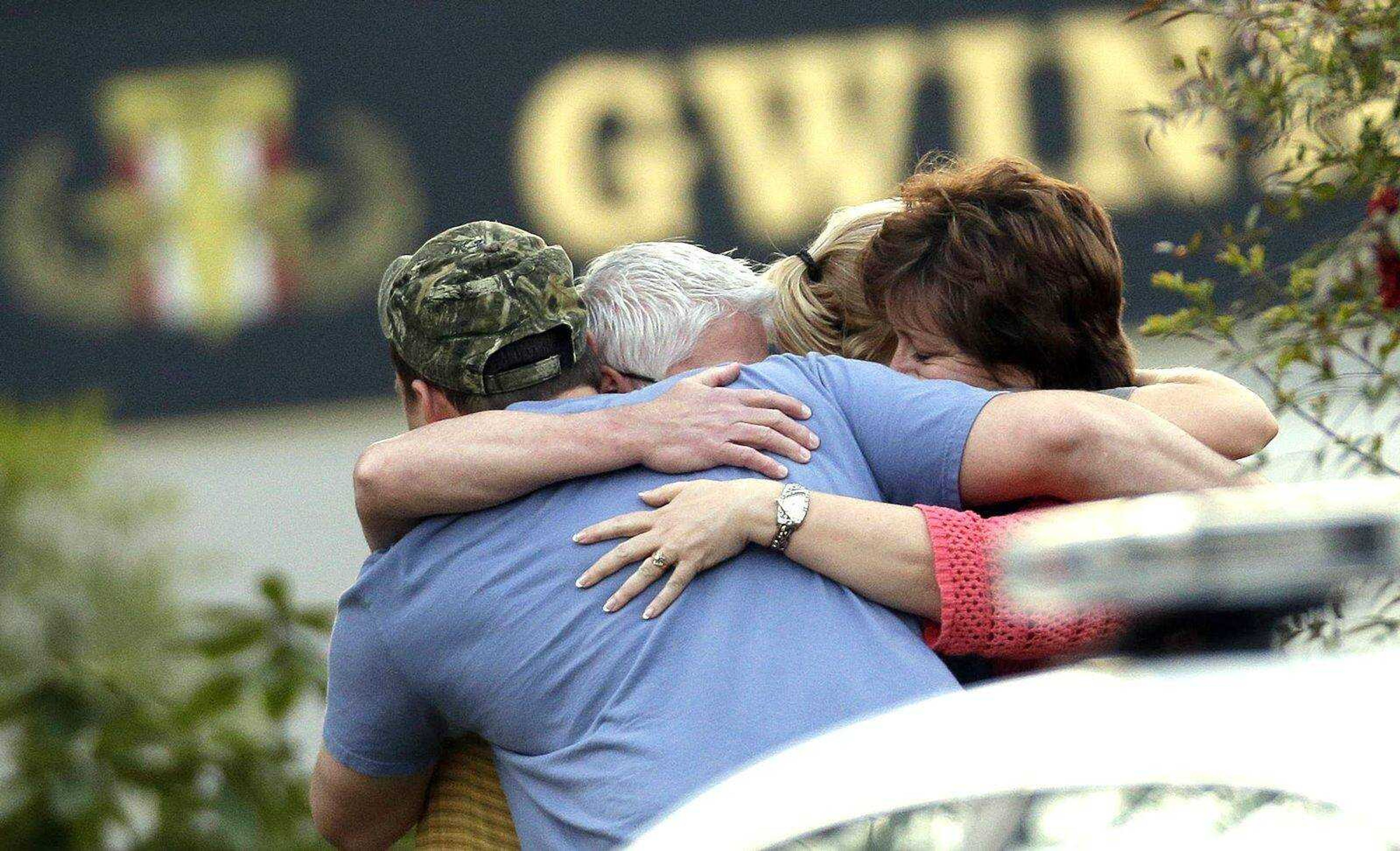 A group of people huddle together after an explosion and gunshots were heard near the scene where a man was holding four firefighters hostage Wednesday in Suwanee, Ga. (John Bazemore ~ Associated Press)