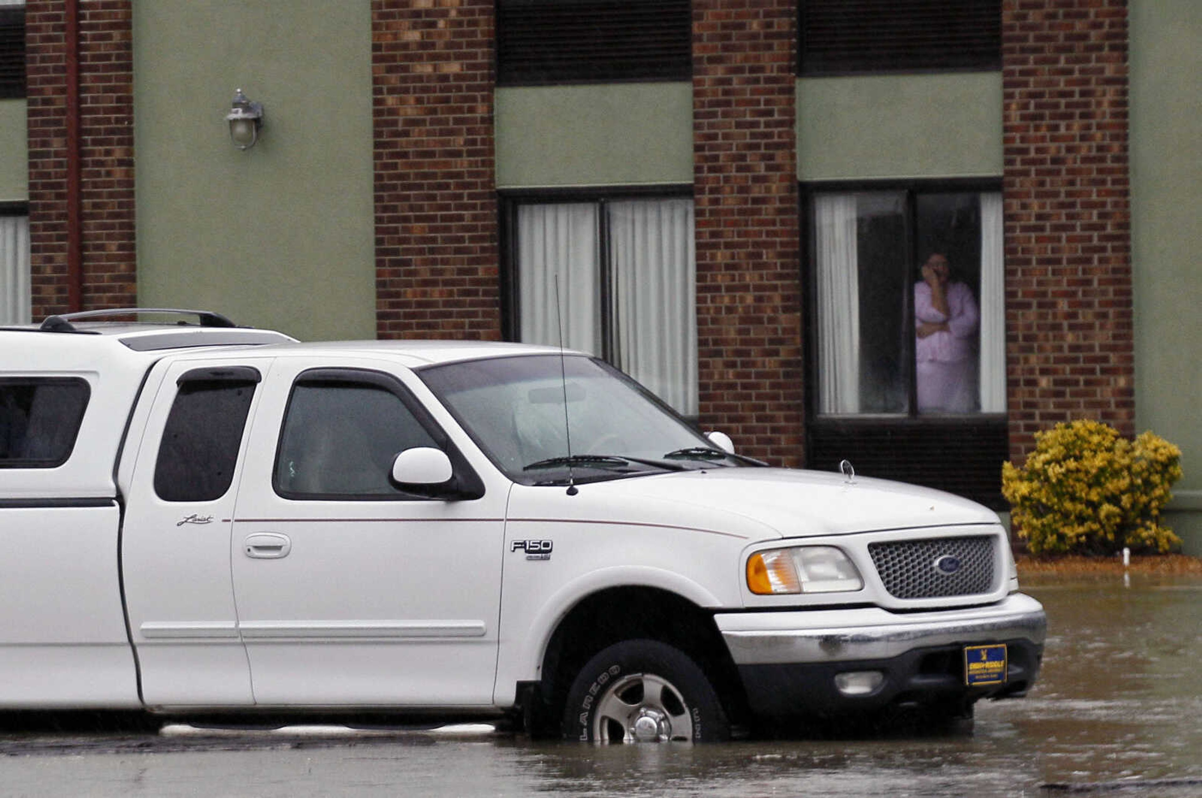 A lady peers from a hotel room as floodwaters generated by strong rain and wind rise around a truck in a parking lot as Hurricane Sandy moves up the east coast in Kitty Hawk, N.C., Monday, Oct. 29, 2012. Hurricane Sandy continued on its path Monday, as the storm forced the shutdown of mass transit, schools and financial markets, sending coastal residents fleeing, and threatening a dangerous mix of high winds and soaking rain.Ę (AP Photo/Gerry Broome)