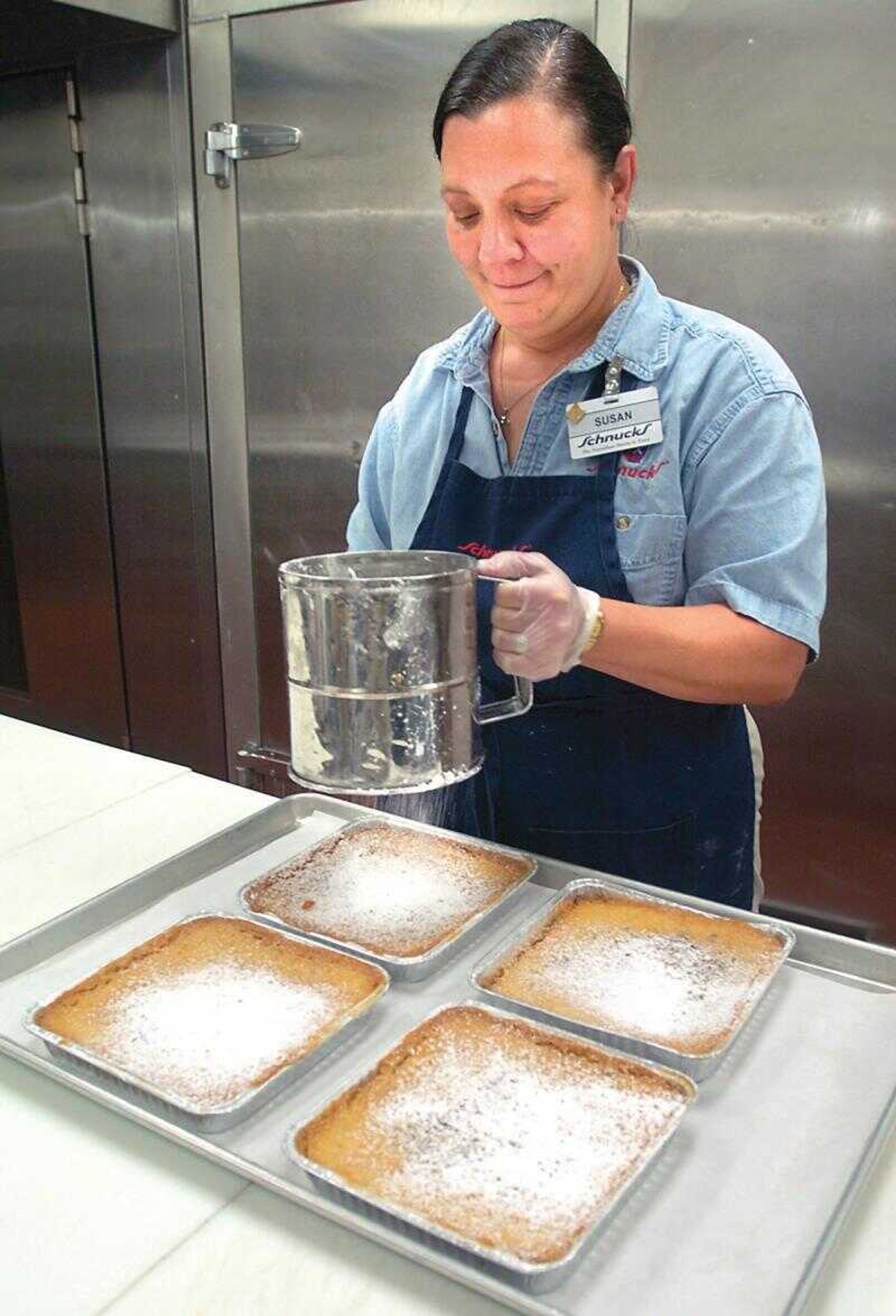 Susan Wahlers sprinkled powdered sugar onto gooey butter cakes at Schnucks in Cape Girardeau.