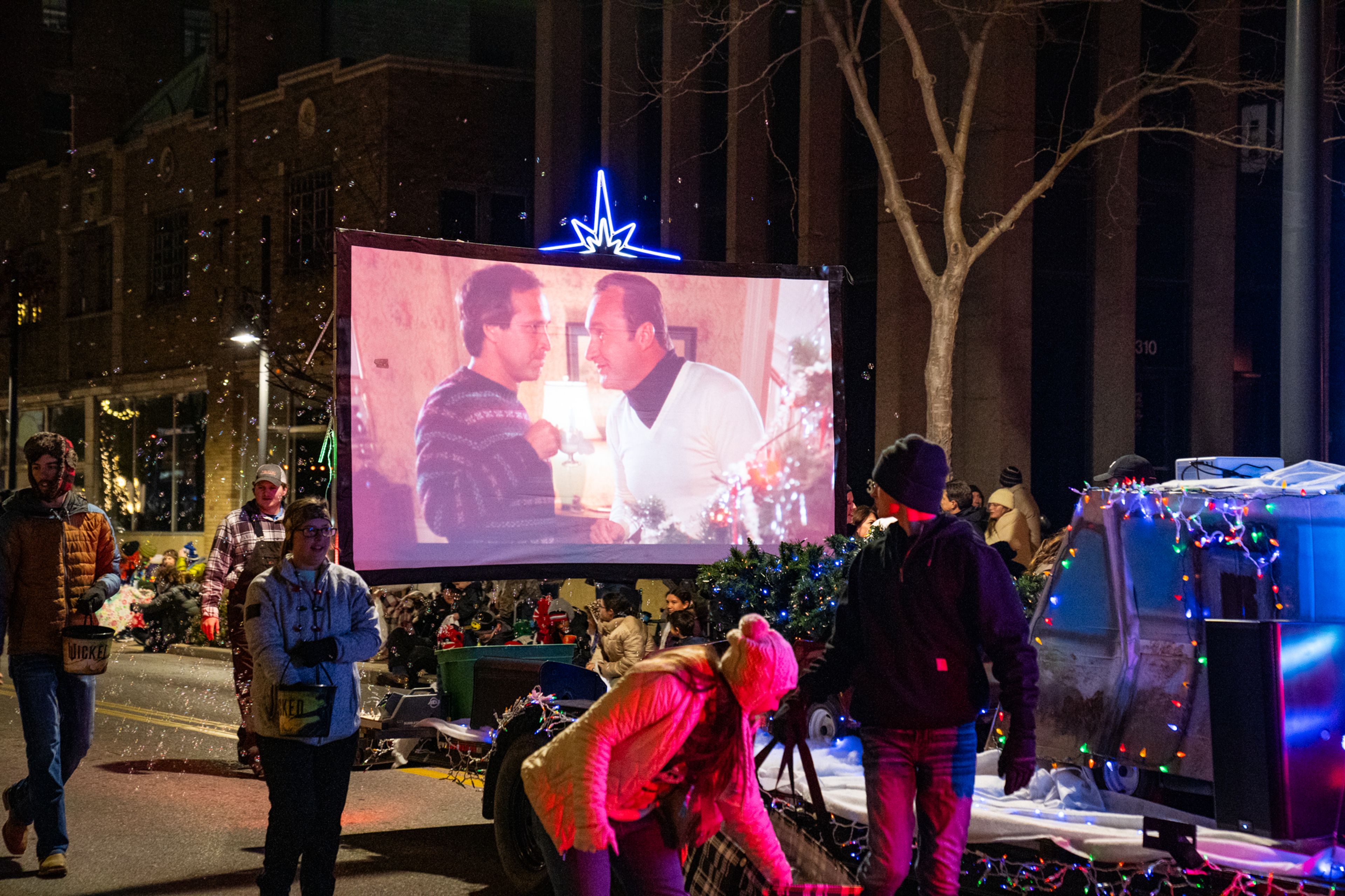 The Rock 'N' Roll Drive-In Theater presents National Lampoon's Christmas Vacation on a screen as they drive through the parade.