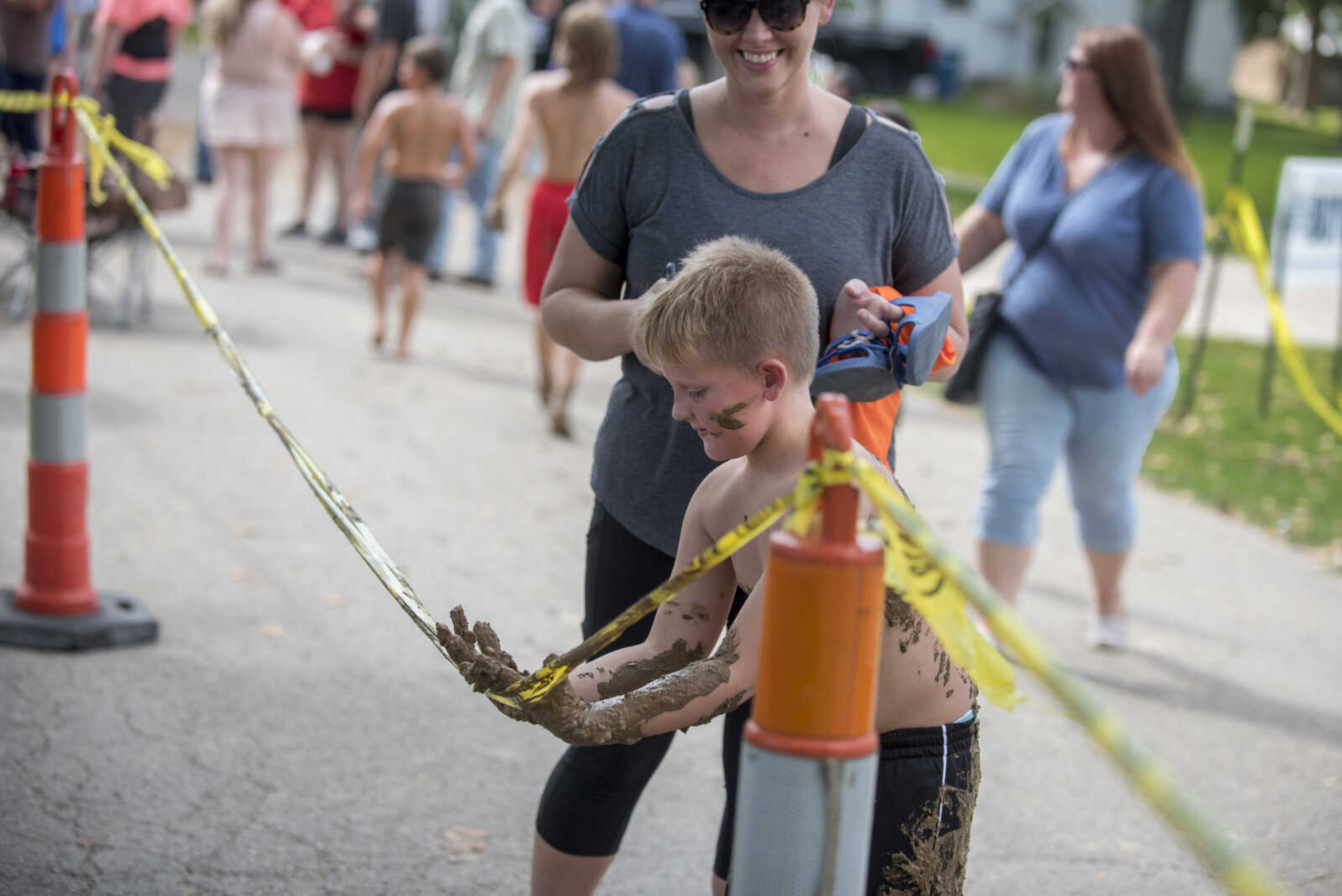 Bailey Elkins, 7, tries to wipe mud off his hands after a mud race during Benton Neighbor Days Saturday, September 1, 2018.