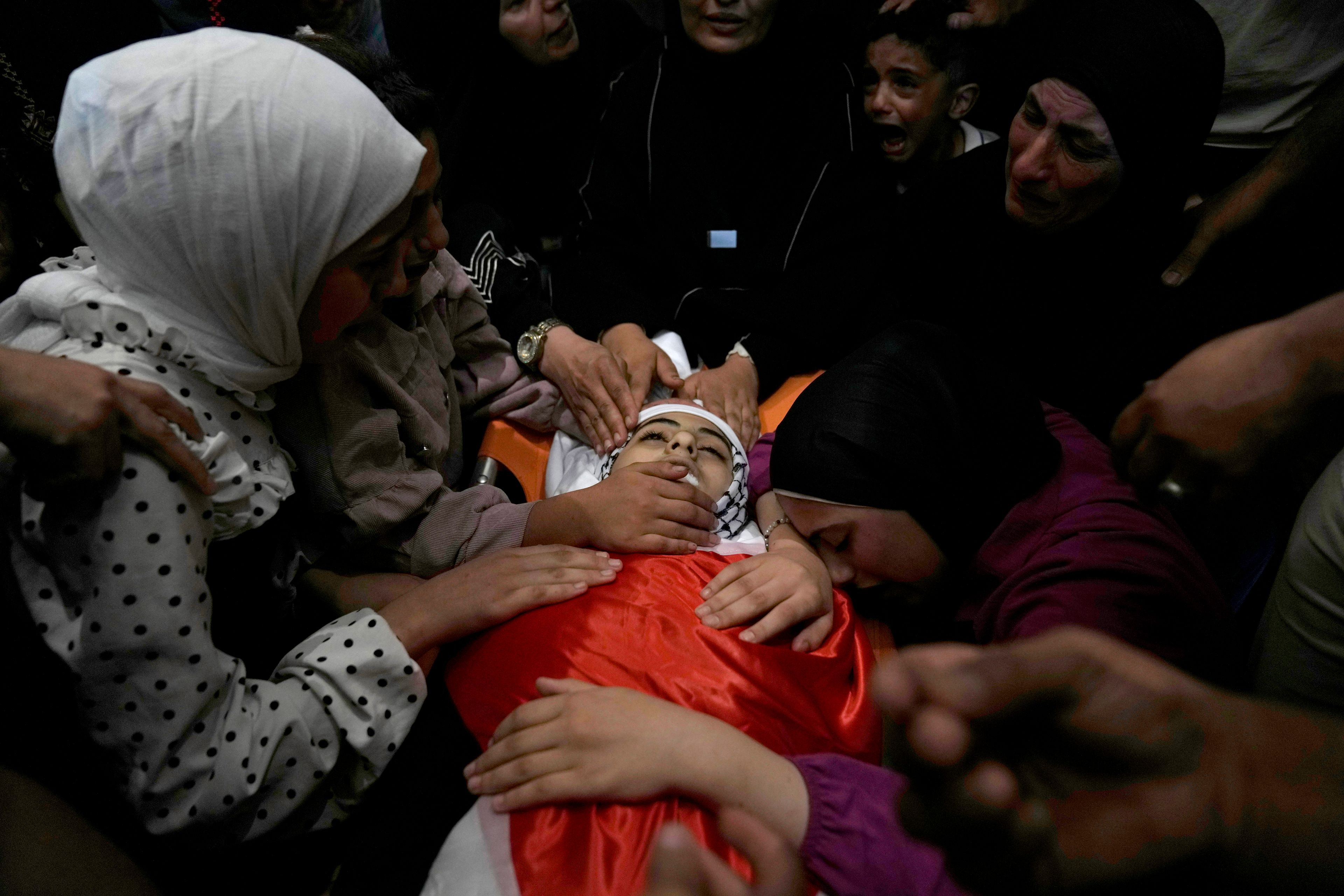 Mourners take the last look at the body of Palestinian girl Bana Bakr, 13, at the family house during her funeral in the West Bank village of Qaryut, south of Nablus, Saturday, Sept. 7, 2024. Bakr was killed by Israeli fire, the Palestinian health ministry said. The Israeli army said they were reviewing the incident. (AP Photo/Nasser Nasser)