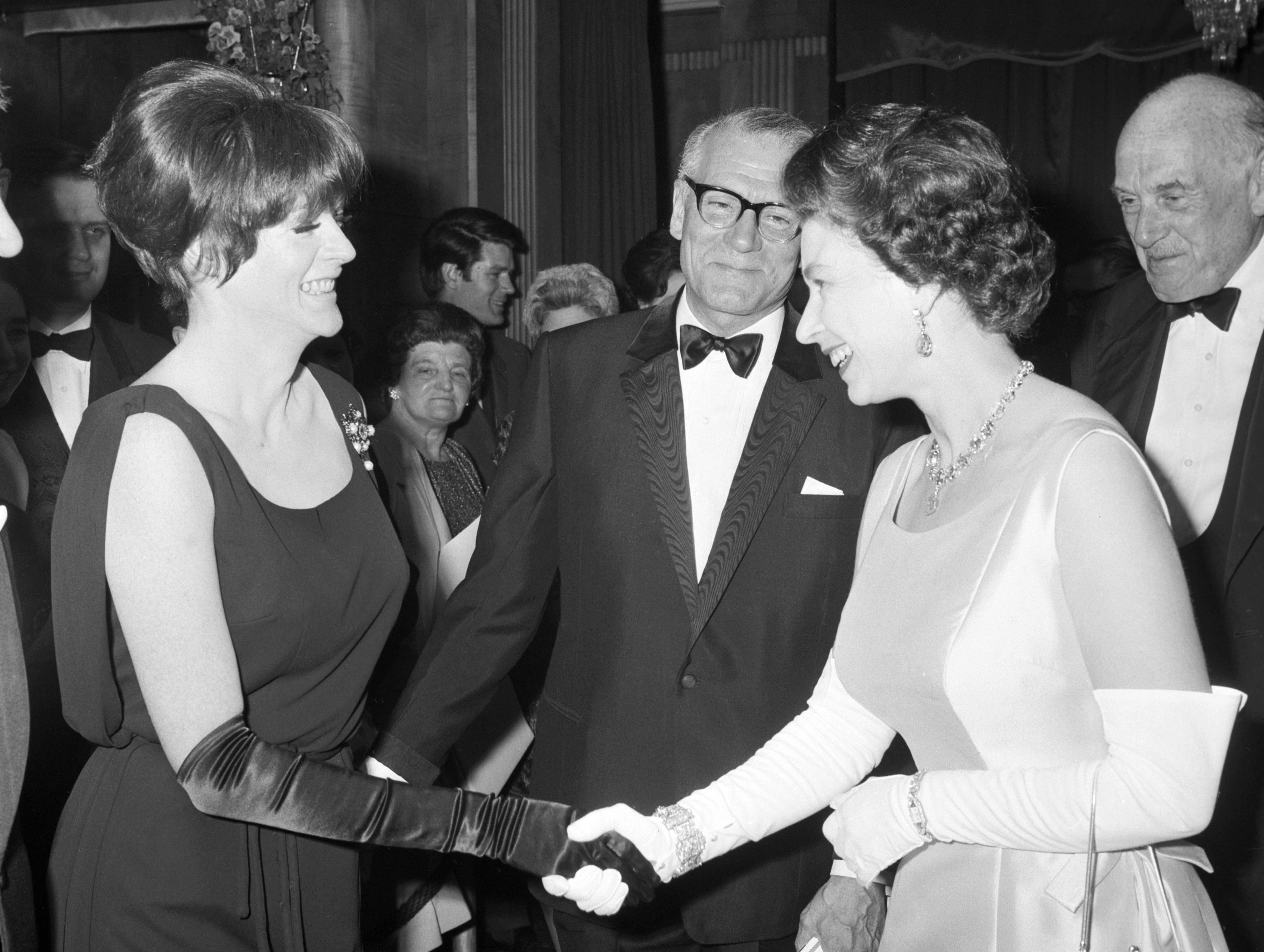 FILE - Britain's Queen Elizabeth II, right is introduced to Maggie Smith by Laurence Olivier, center, during the charity premiere for the film Othello, at the Odeon Theatre, London, May 2, 1966. Smith has died aged 89. (PA via AP, File)