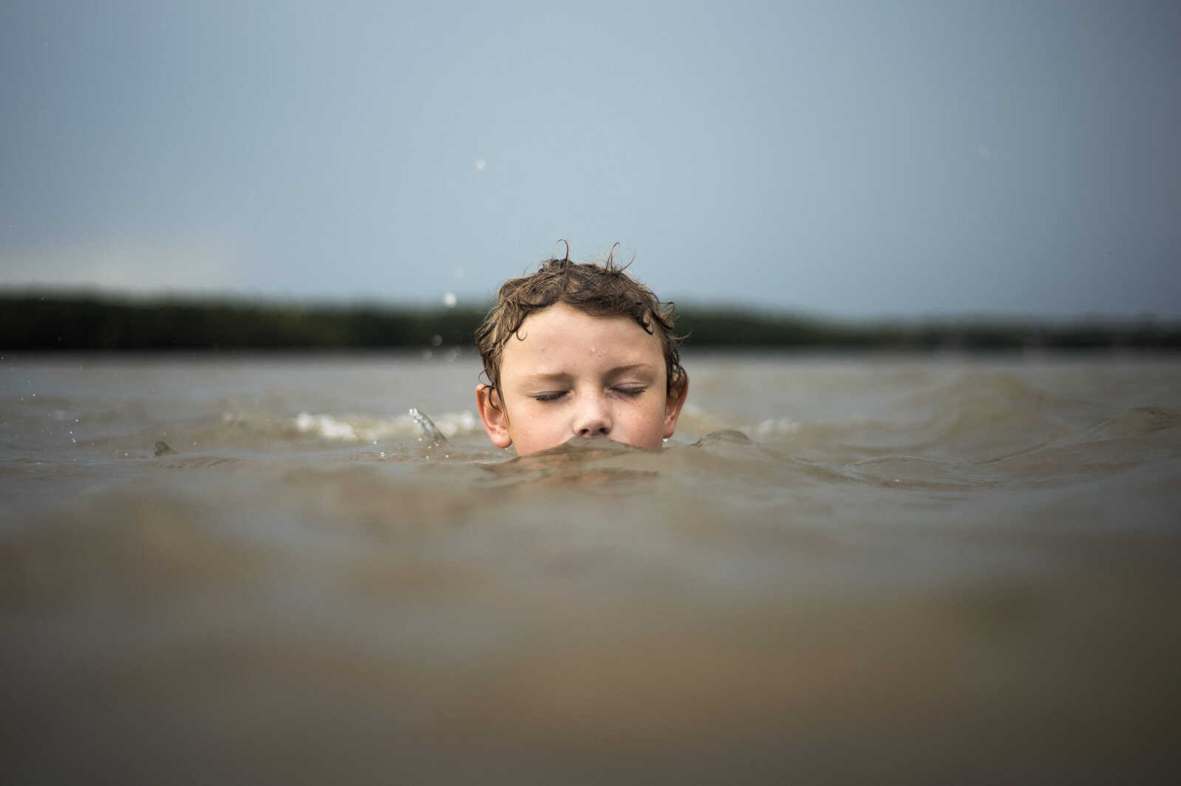 Robert Laird, 10, closes his eyes while attempting to maintain his balance in the waters of the Mississippi River on Tuesday, Aug. 6, 2019, at Riverfront Park in Cape Girardeau. Joined by his 6-year-old friend Anthony Benson, Laird and Benson swam in the river during an afternoon rainstorm while his mother watched over the two.