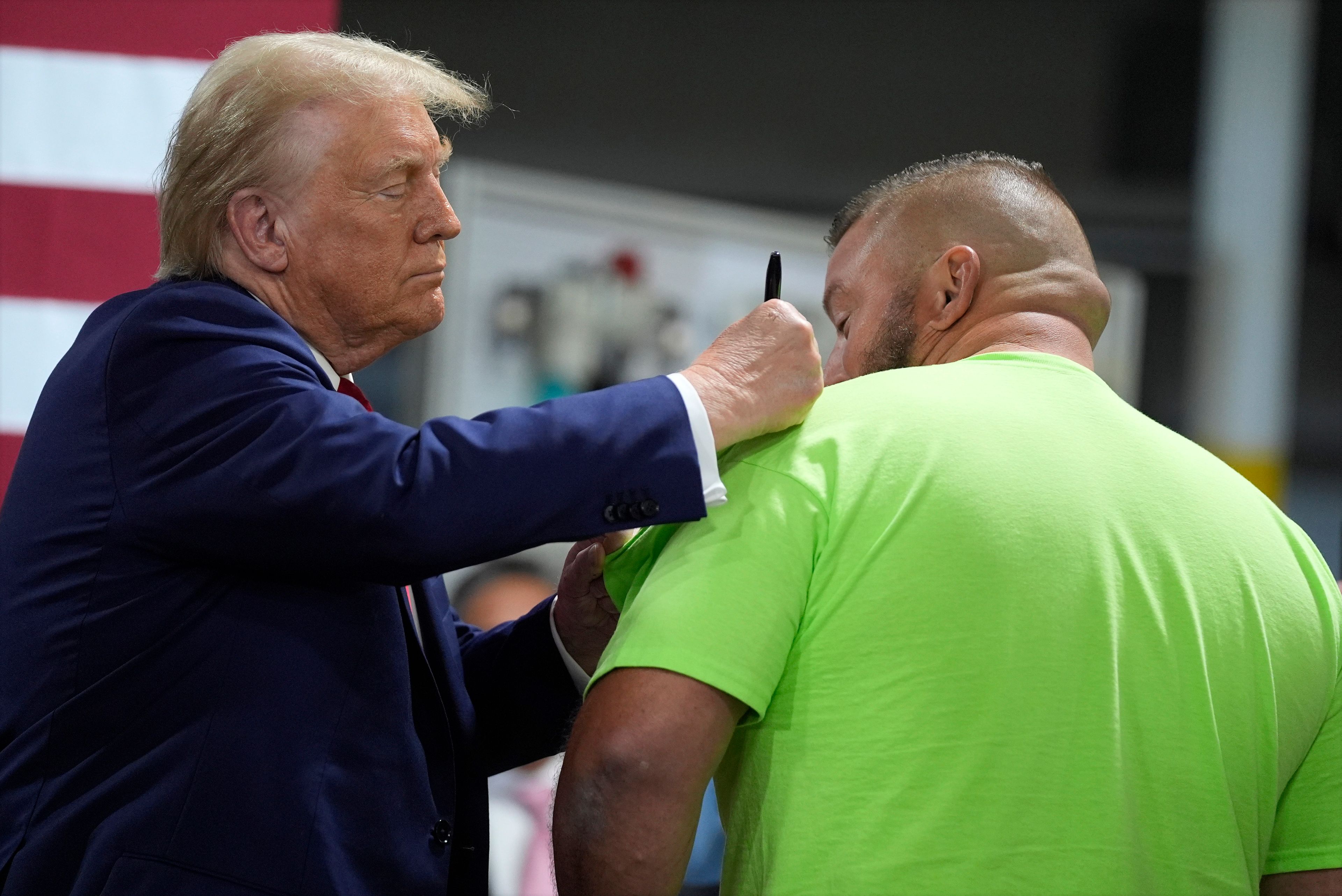 Republican presidential nominee former President Donald Trump autographs a short after speaking at a campaign roundtable, Friday, Oct. 18, 2024, in Auburn Hills, Mich. (AP Photo/Evan Vucci)