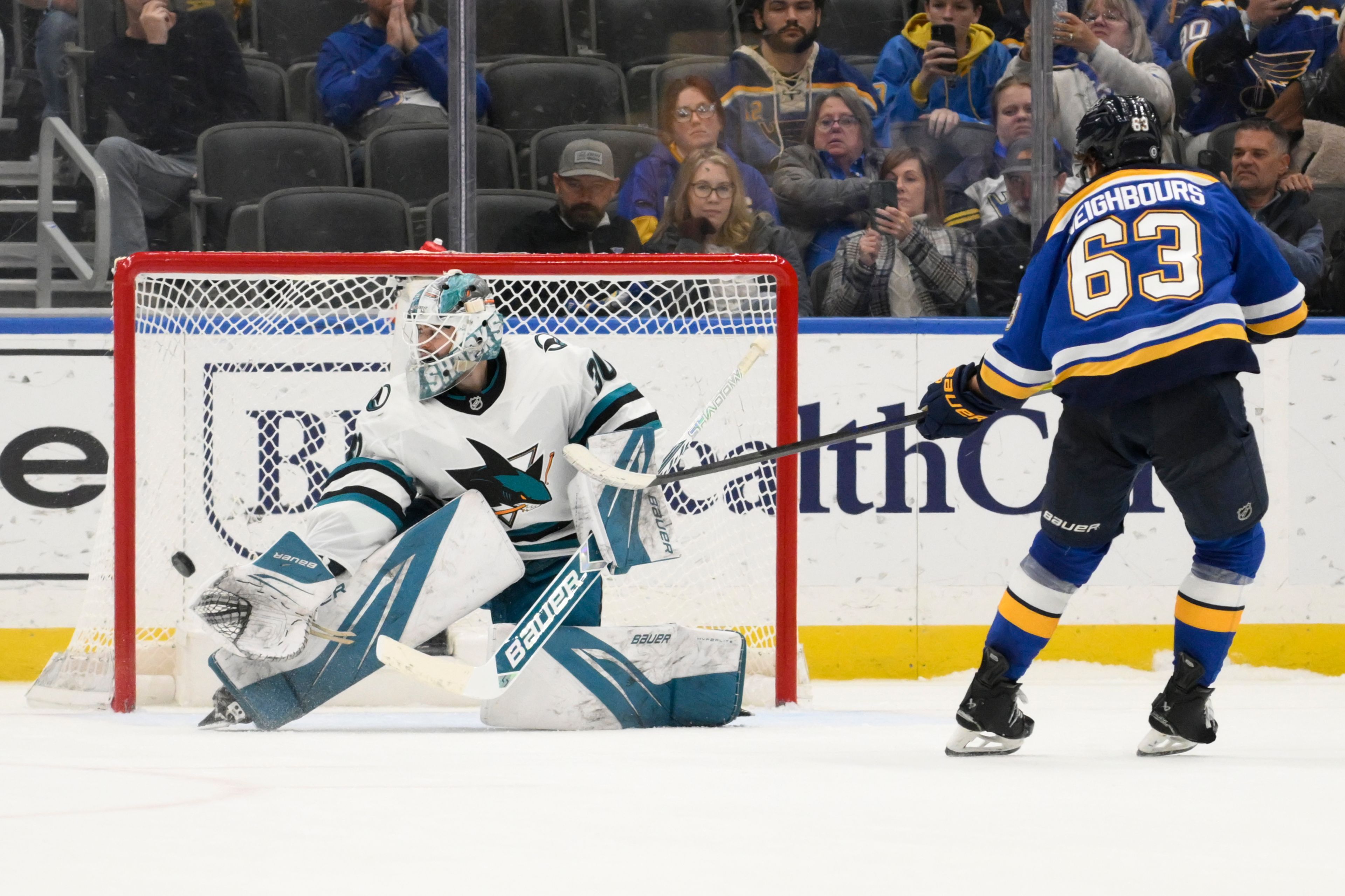 St. Louis Blues left wing Jake Neighbours (63) scores the winning goal against San Jose Sharks goaltender Yaroslav Askarov, left, during a shootout in an NHL hockey game Thursday, Nov. 21, 2024, in St. Louis. (AP Photo/Jeff Le)