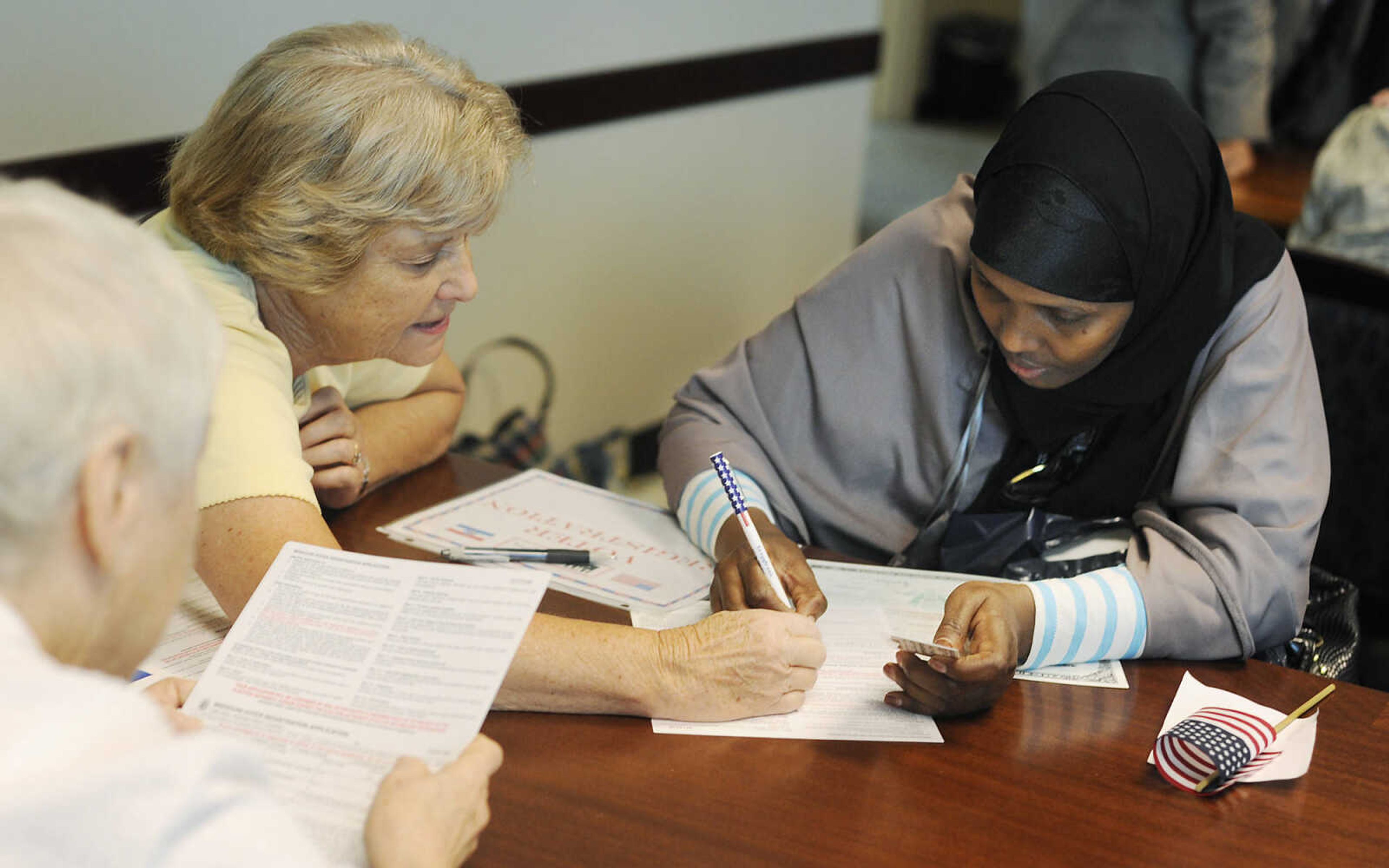 Rosie Schwent, left, helps Fadumo Fakat, who immigrated to the U.S. from Somalia, register to vote after a naturalization ceremony Wednesday, May 1, at the Rush H. Limbaugh Sr. U.S. Courthouse in Cape Girardeau. U.S. District Court Judge Stephen N. Limbaugh administered the oath to 29 people from 11 countries, making them U.S. citizens, during the ceremony.