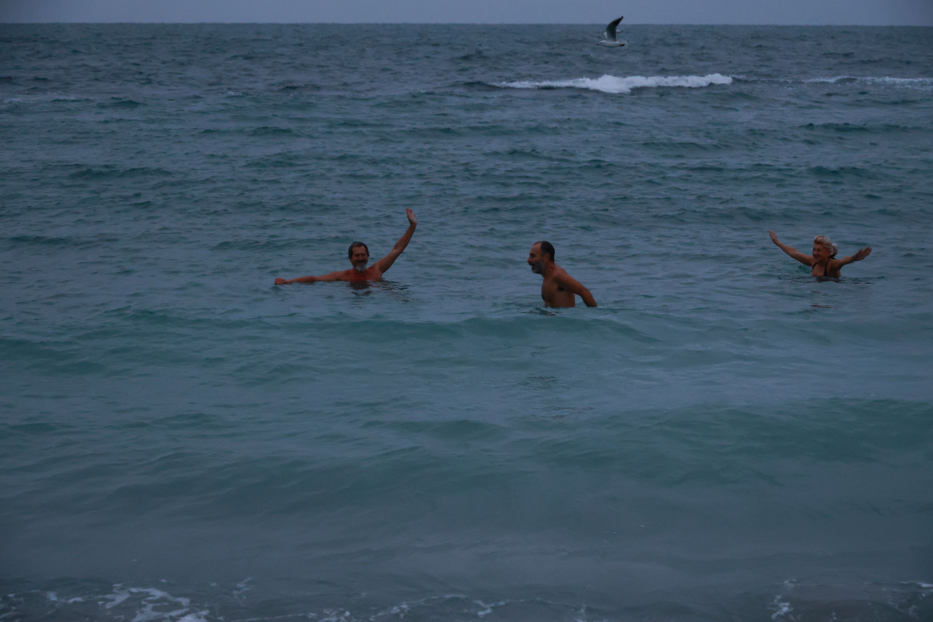 Dmytro, second from left, and his friends swim in the cold water of the Black Sea before sunrise in Odesa, Nov. 11, 2024 (Nina Lyashonok/AP)