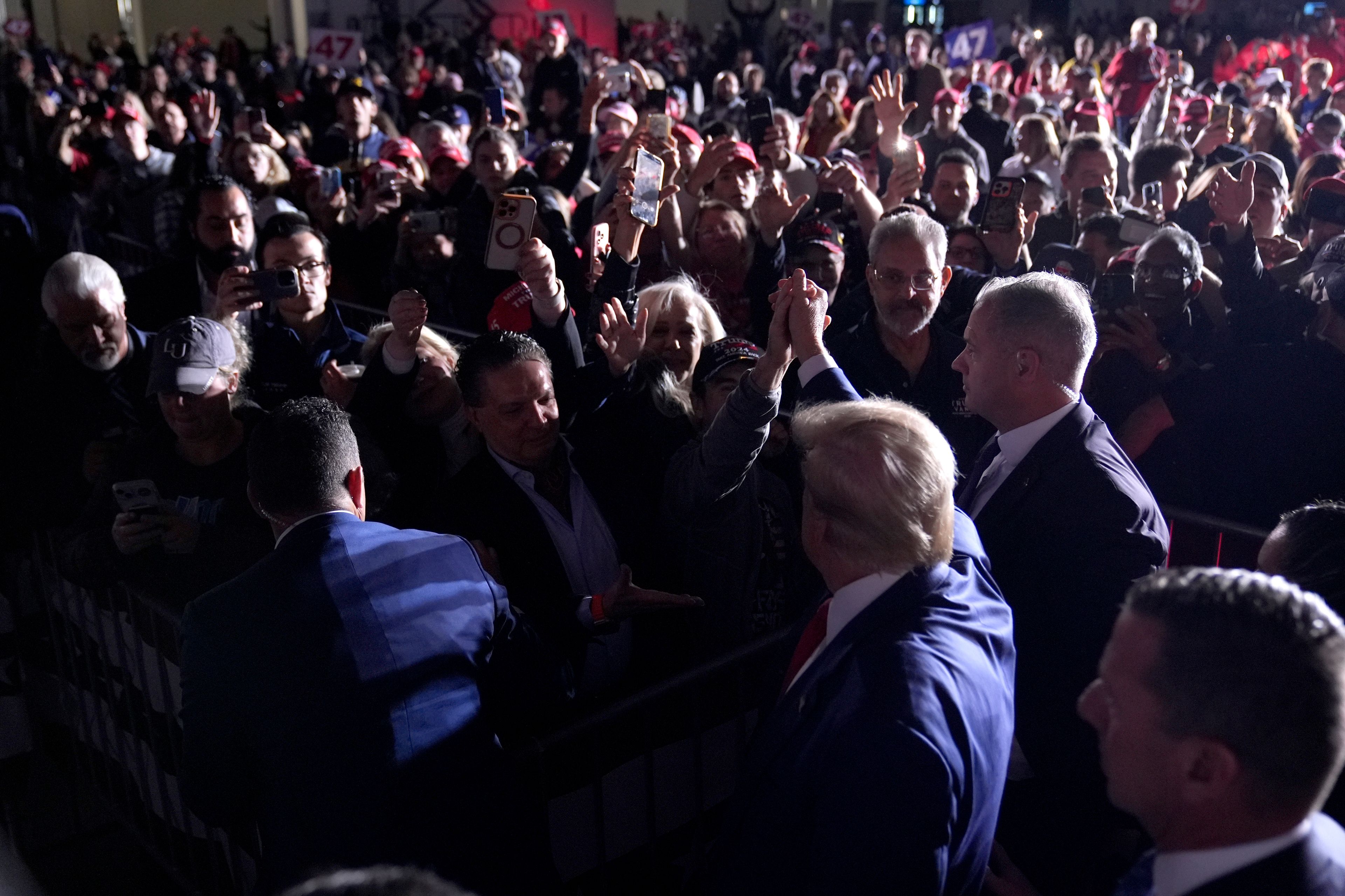 Republican presidential nominee former President Donald Trump, bottom center, greets supporters as he departs after speaking during a campaign rally at the Suburban Collection Showplace, Saturday, Oct. 26, 2024, in Novi, Mich. (AP Photo/Alex Brandon)