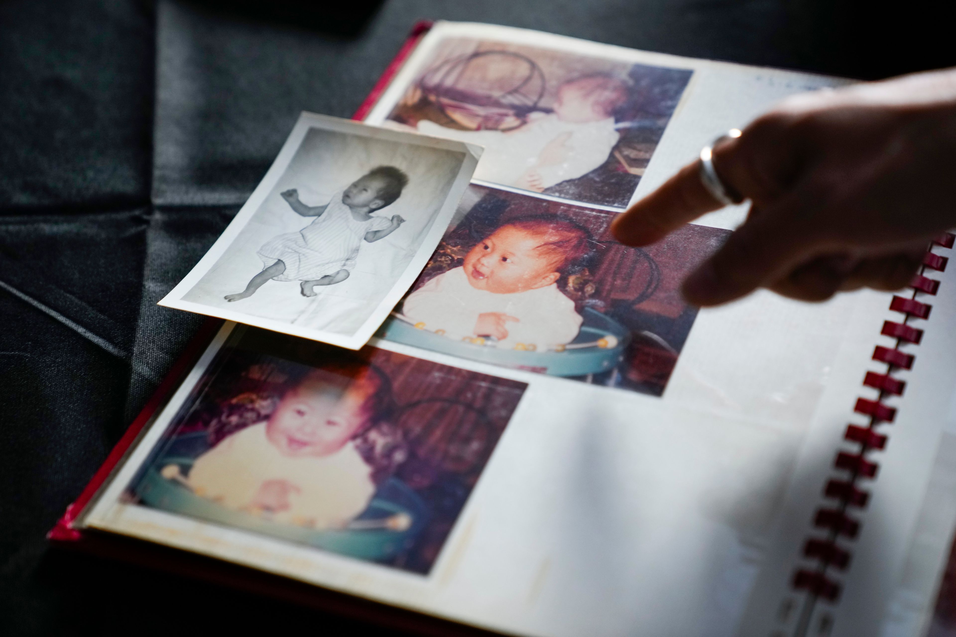 Rebecca Kimmel points to color photos of herself after being adopted, next to a photo of a girl used in her adoption file that she believes is a different baby, Saturday, July 1, 2023, at her art studio in Seattle. AP Photo/Lindsey Wasson)