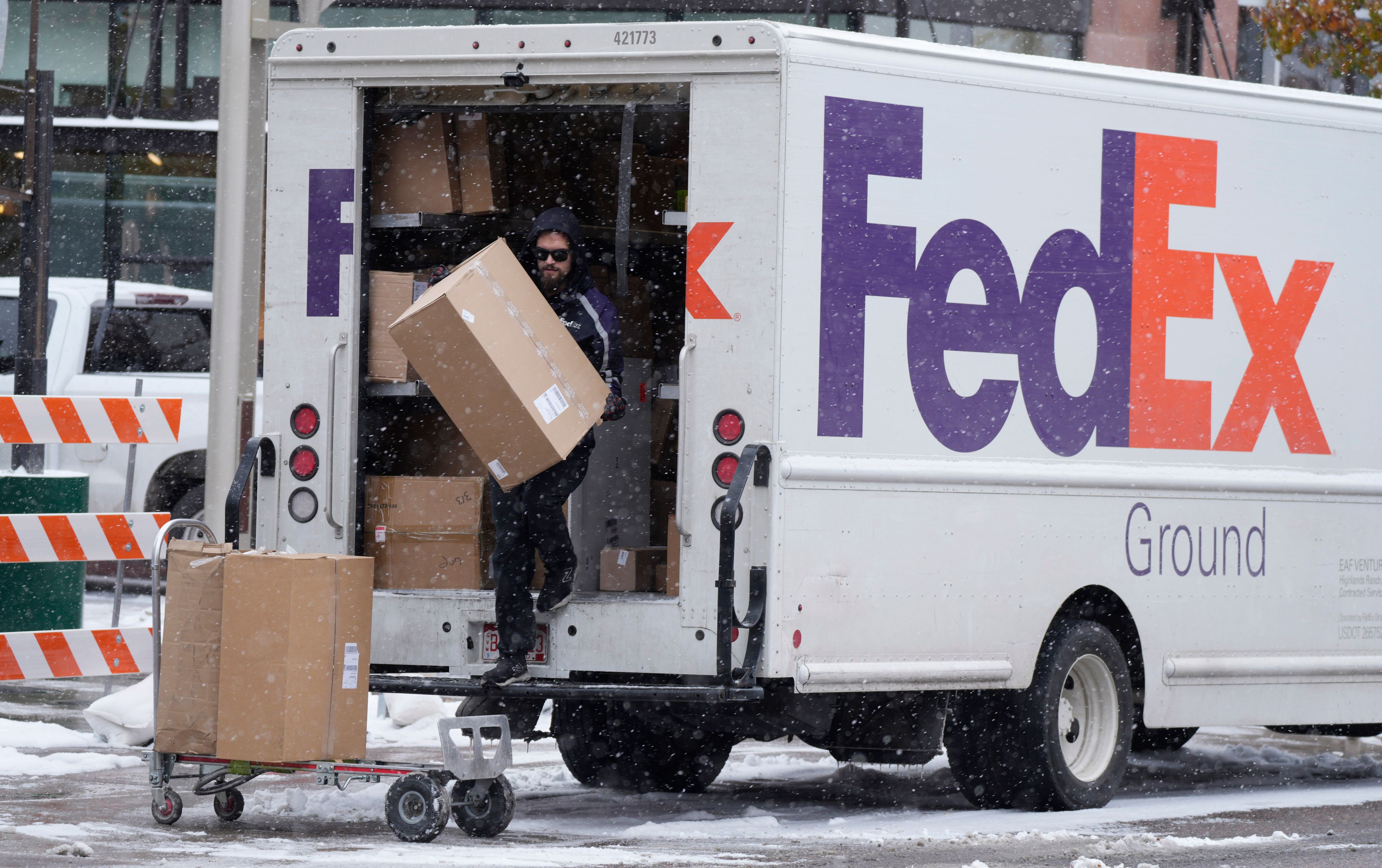 FILE - A FedEx delivery person carries a package from a truck on Nov. 17, 2022, in Denver. (AP Photo/David Zalubowski, File)