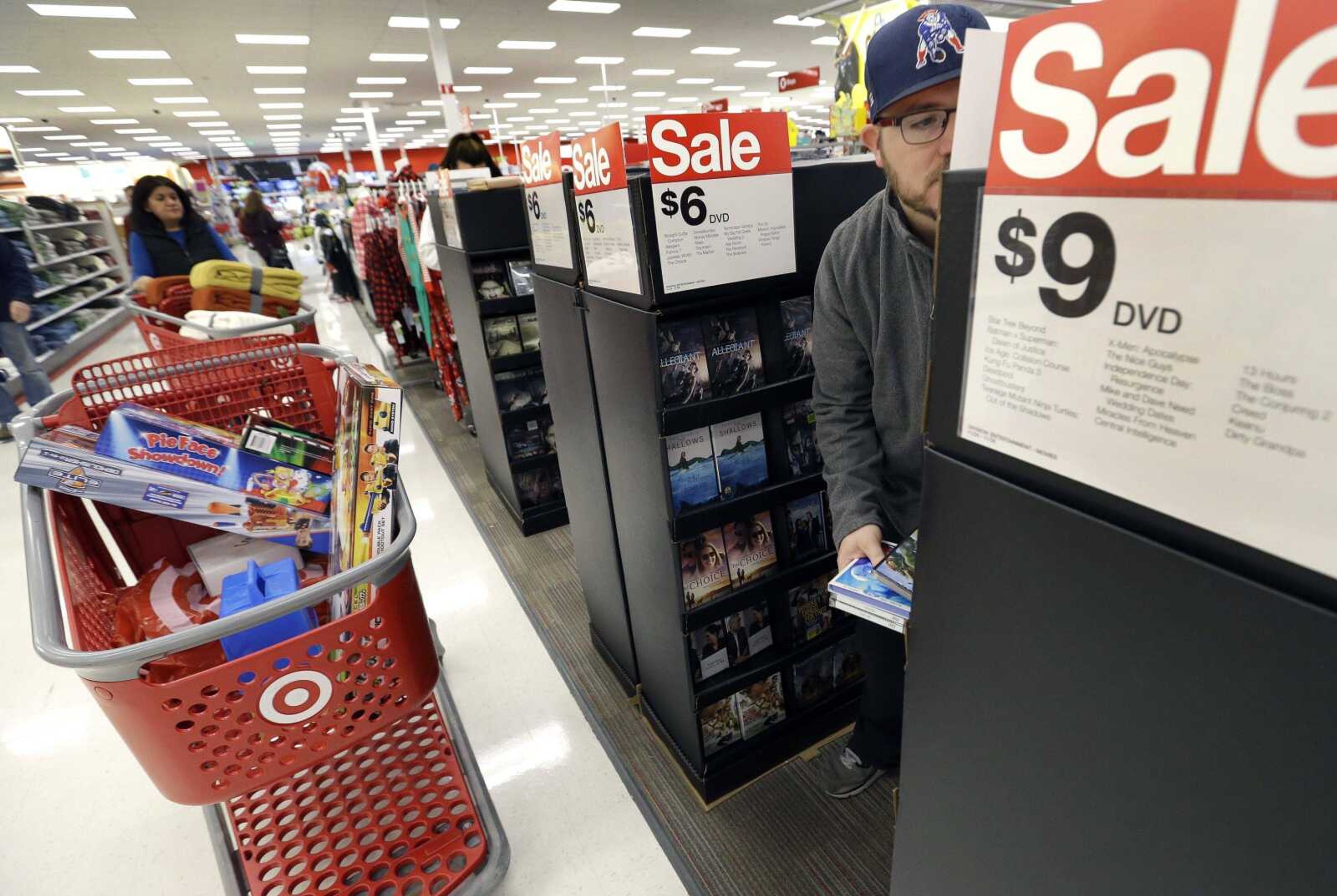 Paul Poirier shops for sales at a Target store in Wilmington, Massachusetts. Retailers are pushing promotions and other enticements for the final stretch of the holiday season as new numbers show shoppers are spending at a decent but a slightly slower rate compared to last year.