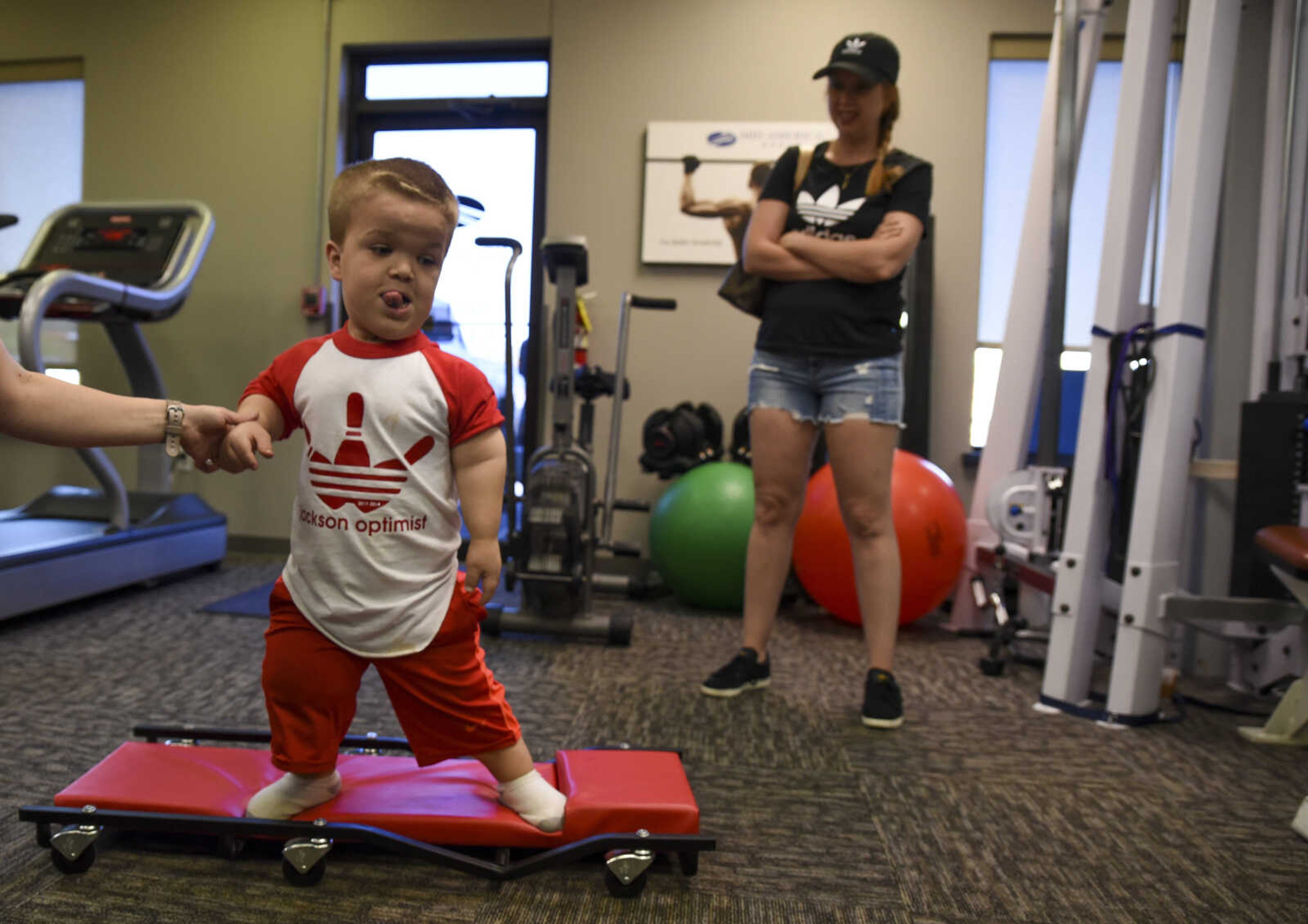 Izaac Pursley sticks his tongue out in focus while he holds physical therapist Katie Schaal's hand as he performs a physical therapy exercise and his mom Sheree Pursley watches during his first physical therapy session at Mid America Rehab May 1, 2018, in Cape Girardeau.