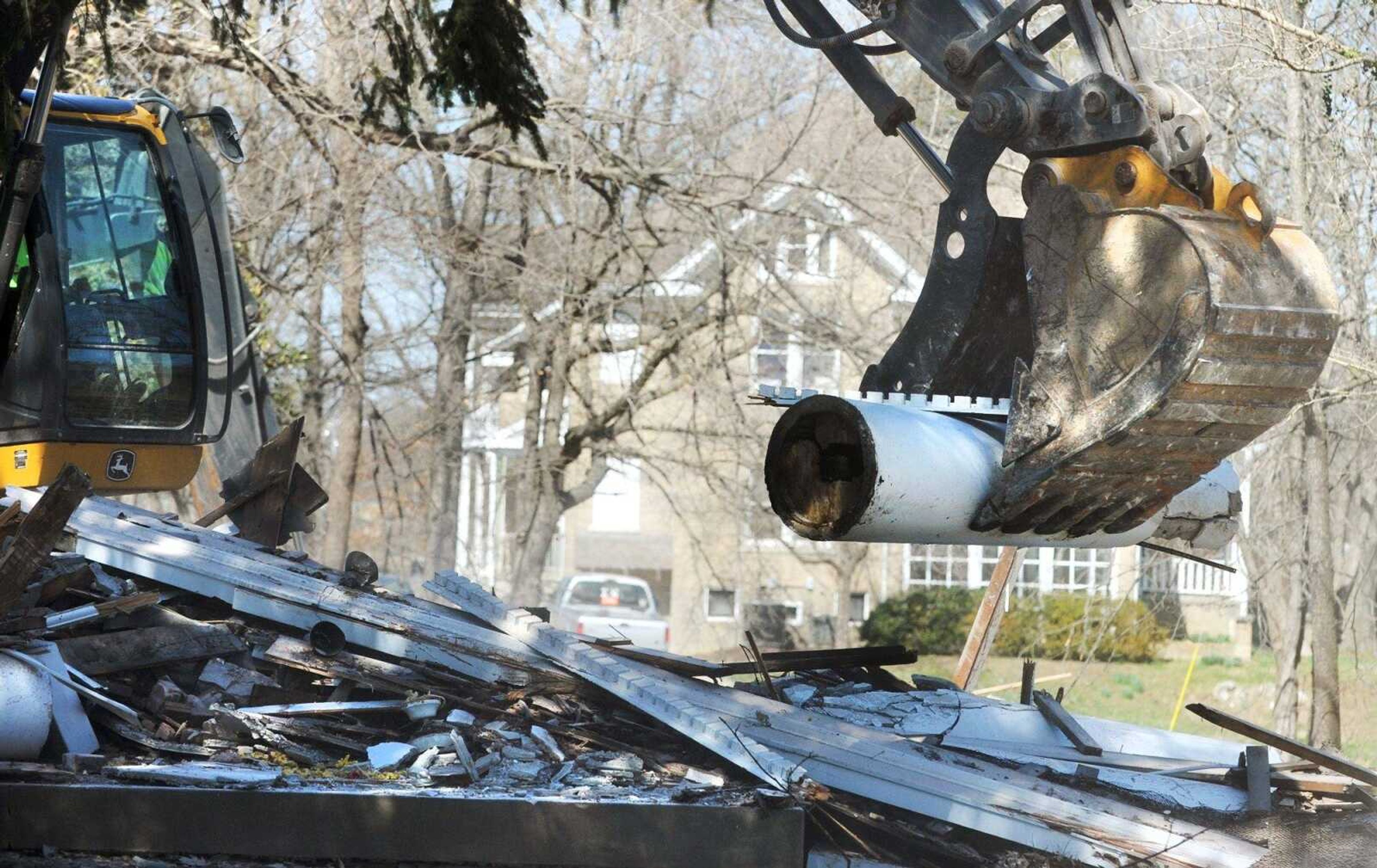 The Ochs-Shivelbine House is seen in the background as an excavator removes rubble from where Greystone Estate stood off of Sprigg Street on March 17. The estate, built in 1921, was used for years by Southeast Missouri State University fraternities. The Ochs-Shivelbine House also is slated for demolition to make way for a planned Greek village by Southeast Missouri State University. (Laura Simon)