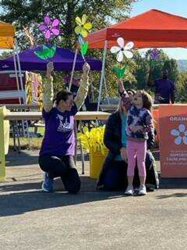 Walk to End Alzheimer's participants hold up flowers that represent different types of connections to Alzheimer's disease. Anyone can register for the walk; it is free to participate, and donations for the cause can be made at alz.org/walk.
