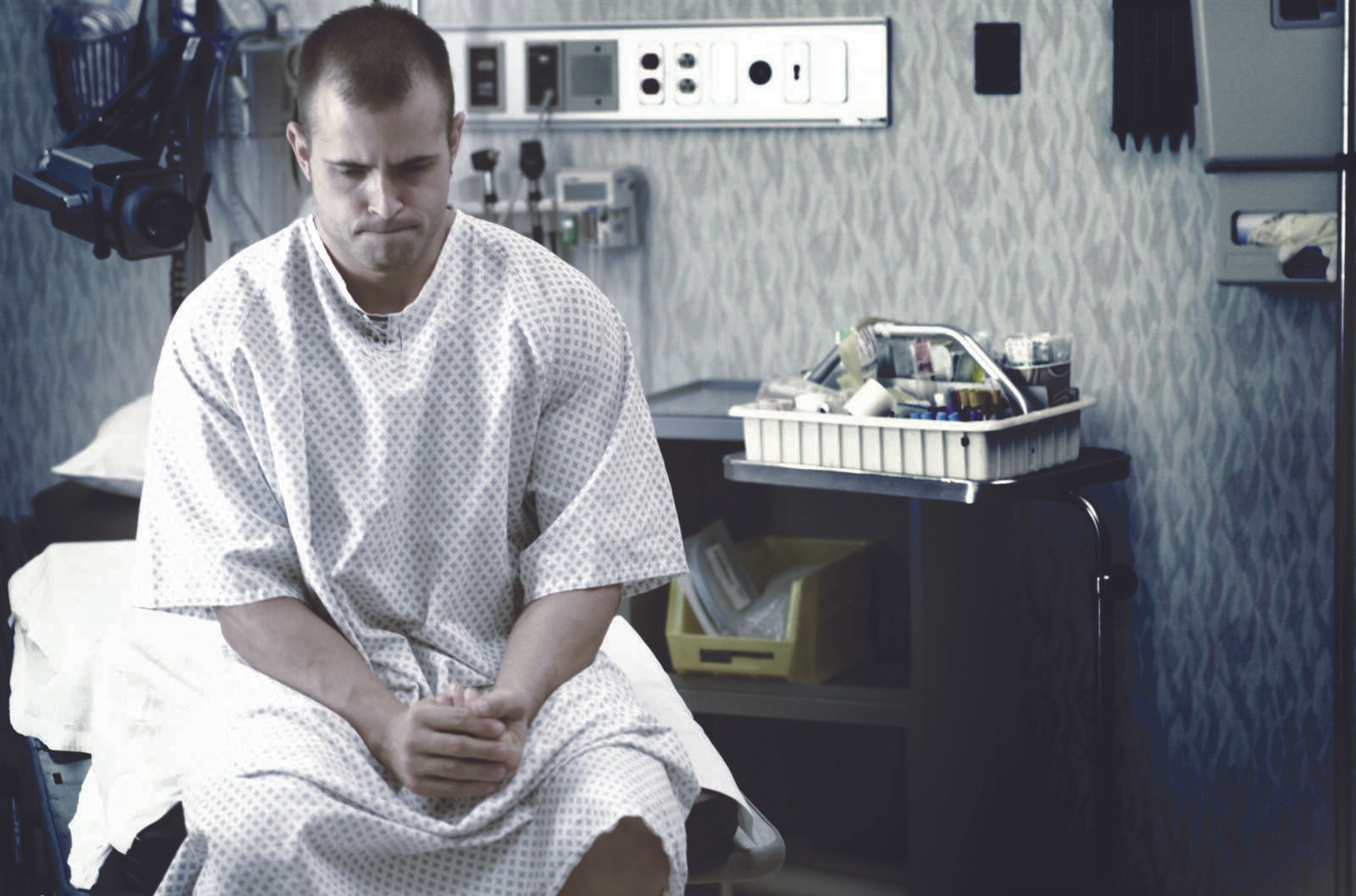 By line:lifestyle photo of a young caucasian man as he waits in a hospital examination room