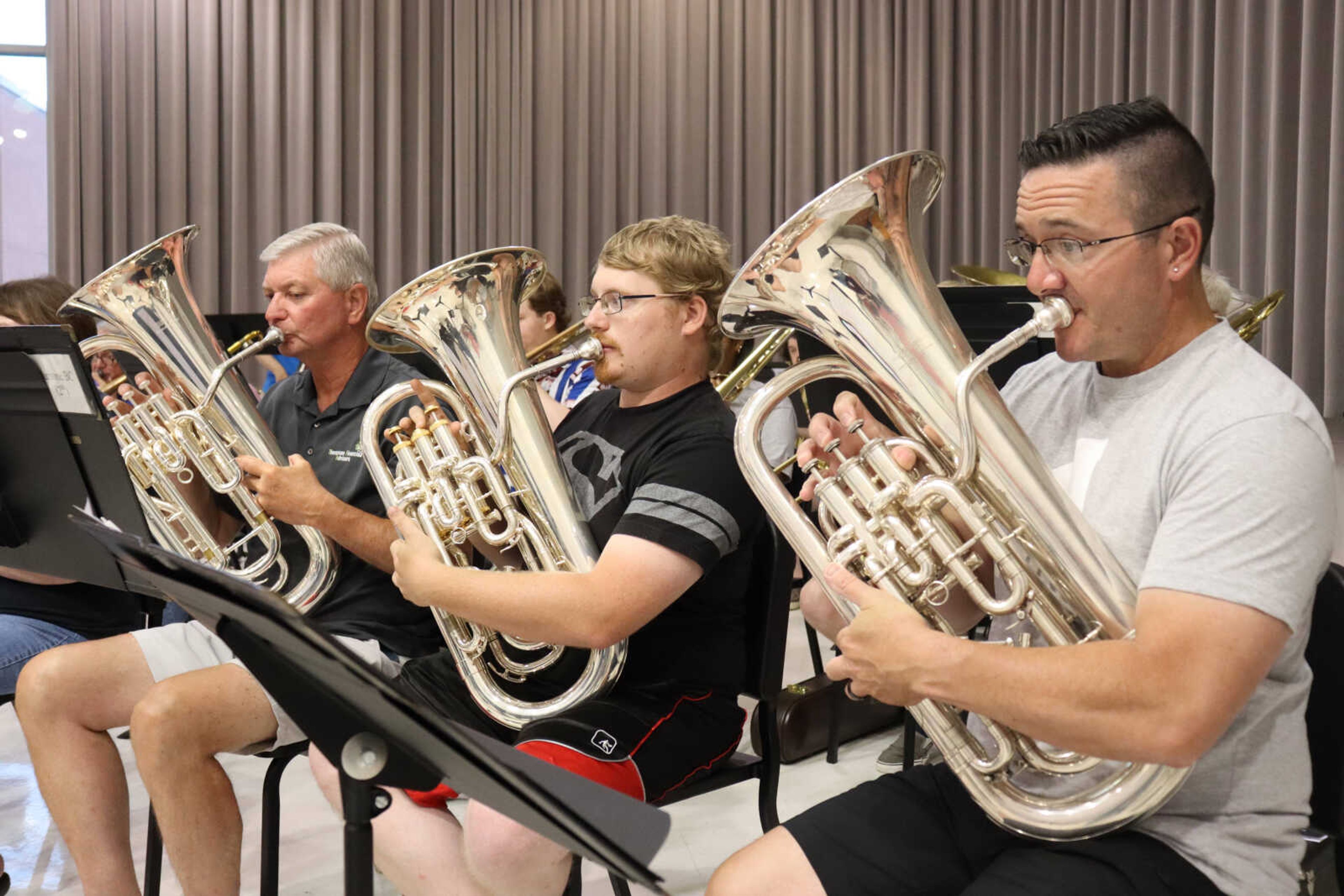 (Left) Baritones John Thompson,  Josh Koenig and Tom Broussard trying to follow along with their arrangements and the director at the practice on Tuesday.