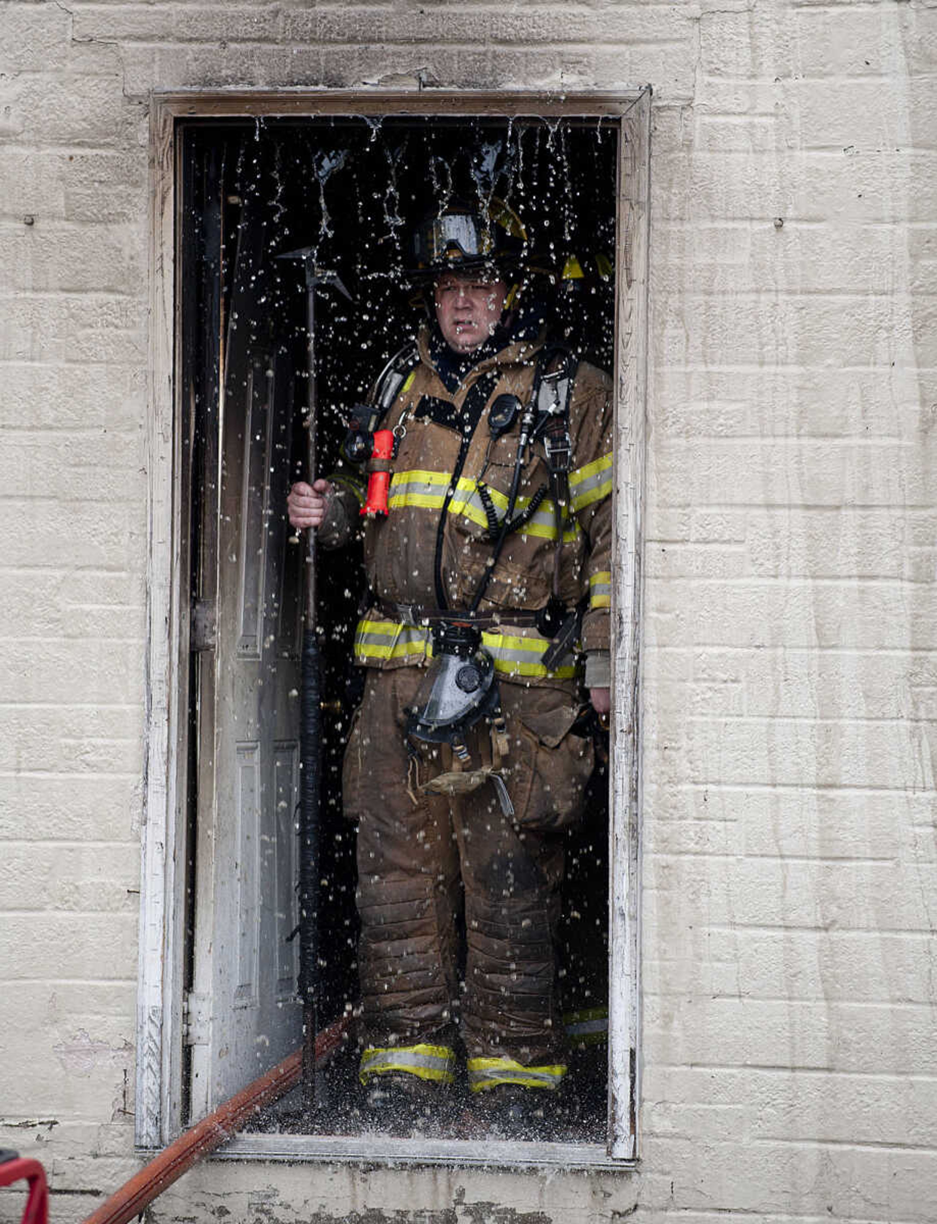 A firefighter peers out the door of a building at 710 Morgan Oak St., as the Cape Girardeau Fire Department battles a structure fire Tuesday, April 29, in Cape Girardeau. A Cape Girardeau Police officer saw the fire and called it in at 1:16 p.m. The building contained two apartments that were home to five people, though no one was home at the time of the fire. The cause of the fire is under investigation.