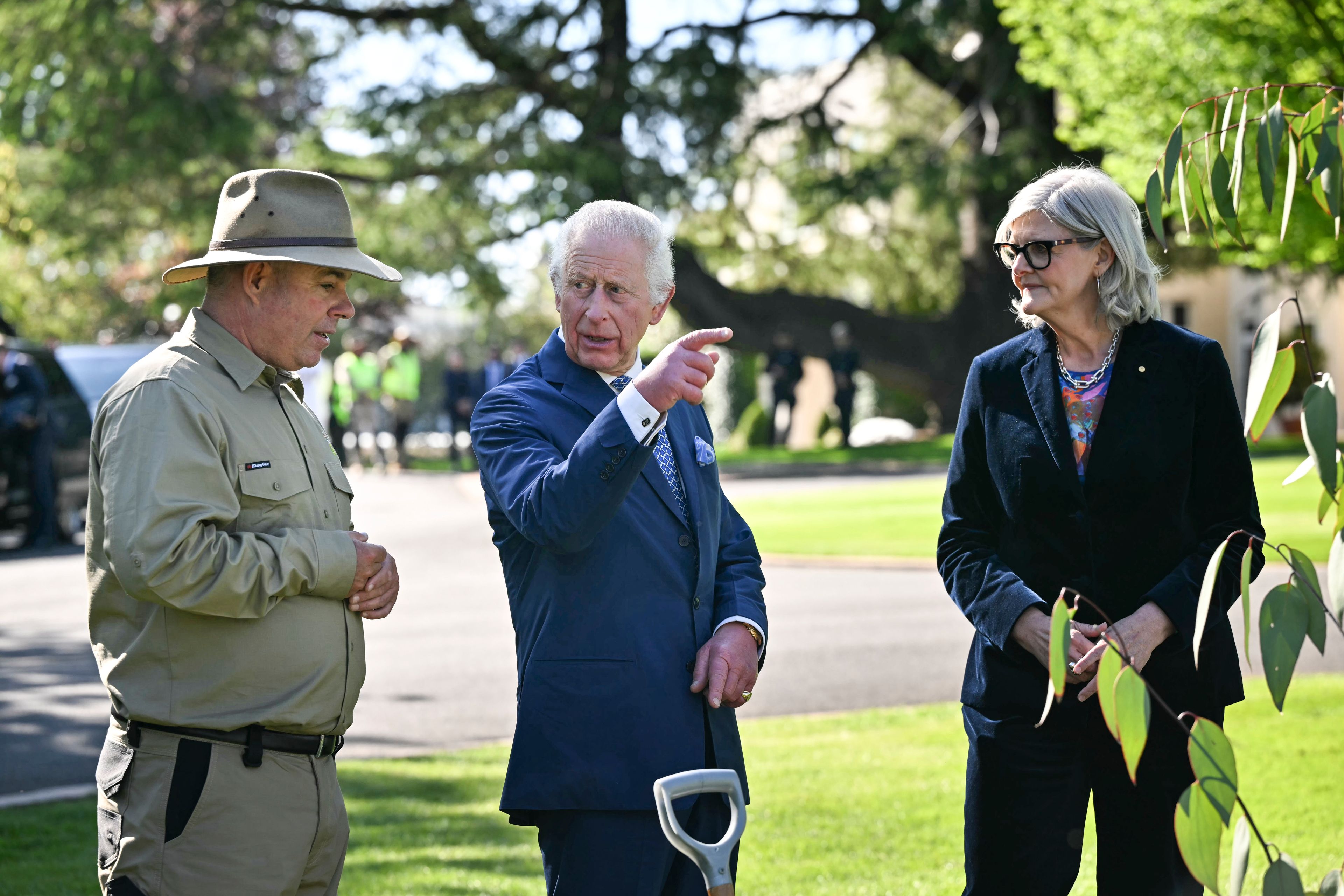 Britain's King Charles III, gestures beside Australia's Governor-General Sam Mostyn right, as he plants a tree at Government House in Canberra, Australia, Monday, Oct. 21, 2024. (Saeed Khan/Pool Photo via AP)