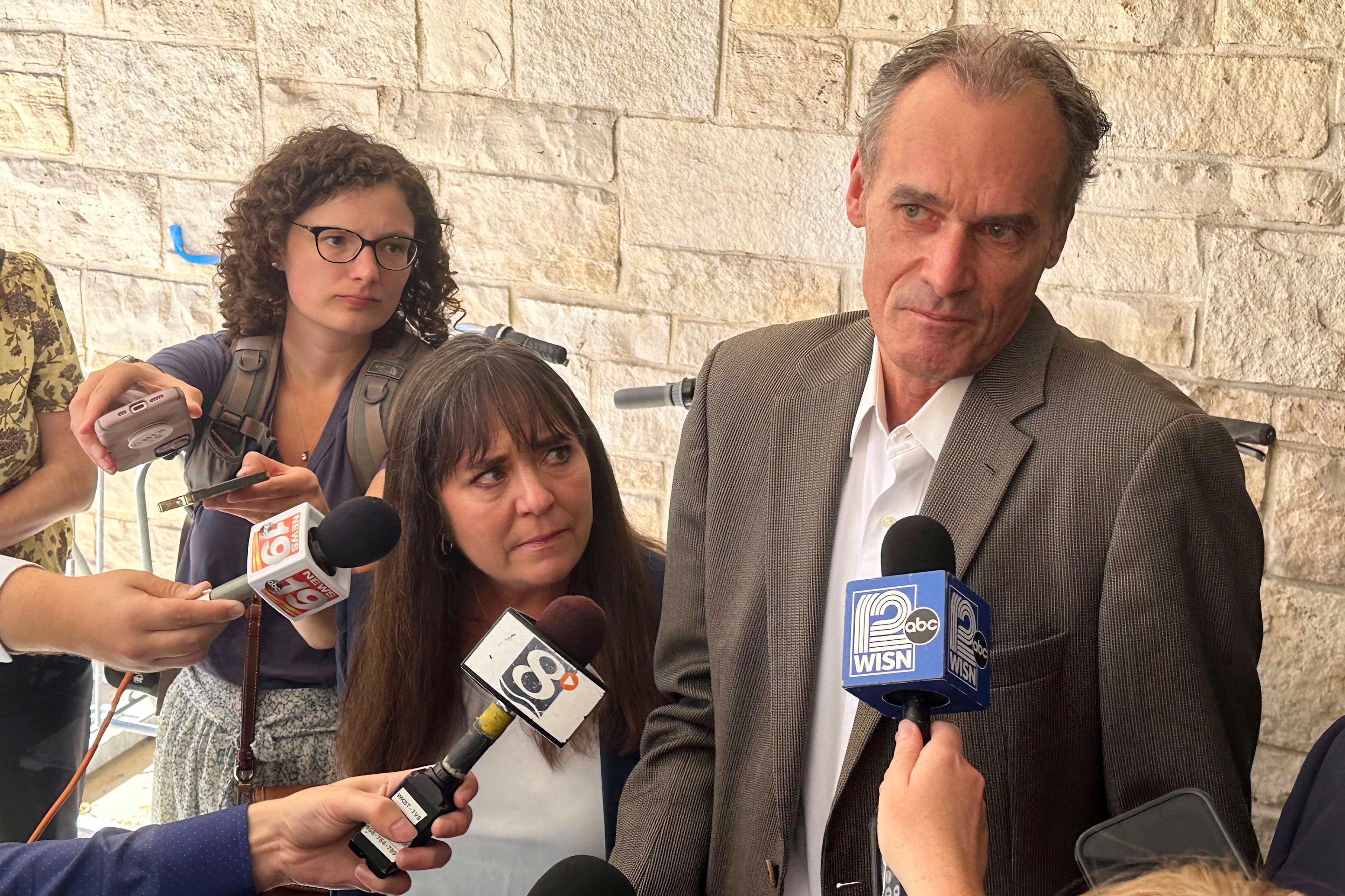 Former University of Wisconsin-La Crosse Chancellor Joe Gow, right, and his wife, Carmen Wilson, center, take questions after a hearing before a committee that will determine whether he can teach after being fired as the campus leader for making pornographic videos, Friday, Sept. 20, 2024, in Madison, Wis. (AP Photo/Scott Bauer)