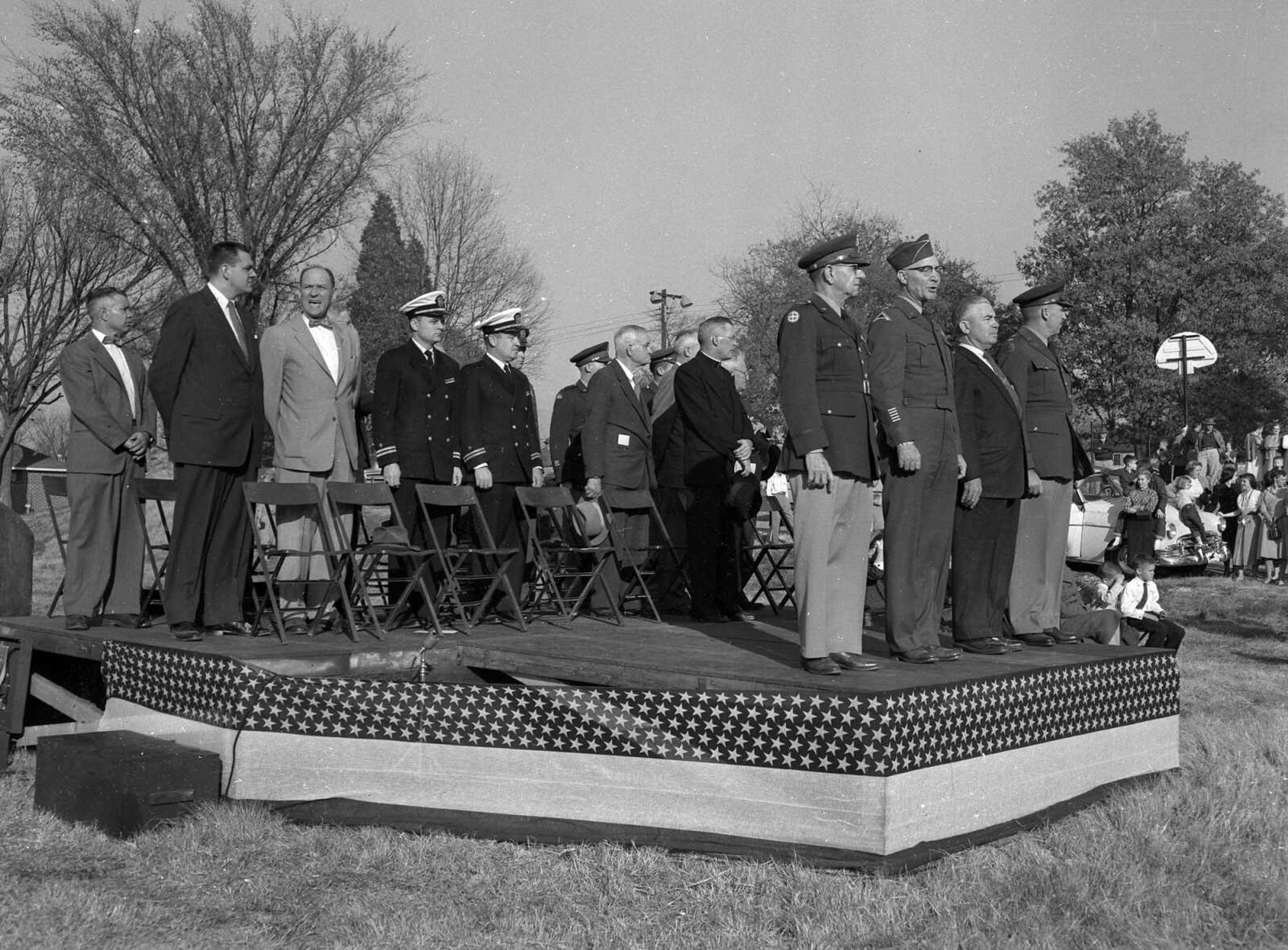 Albert Spradling Jr. and Narvol Randol are among the men on the dais for an unidentified military program. Do you recognize the event?