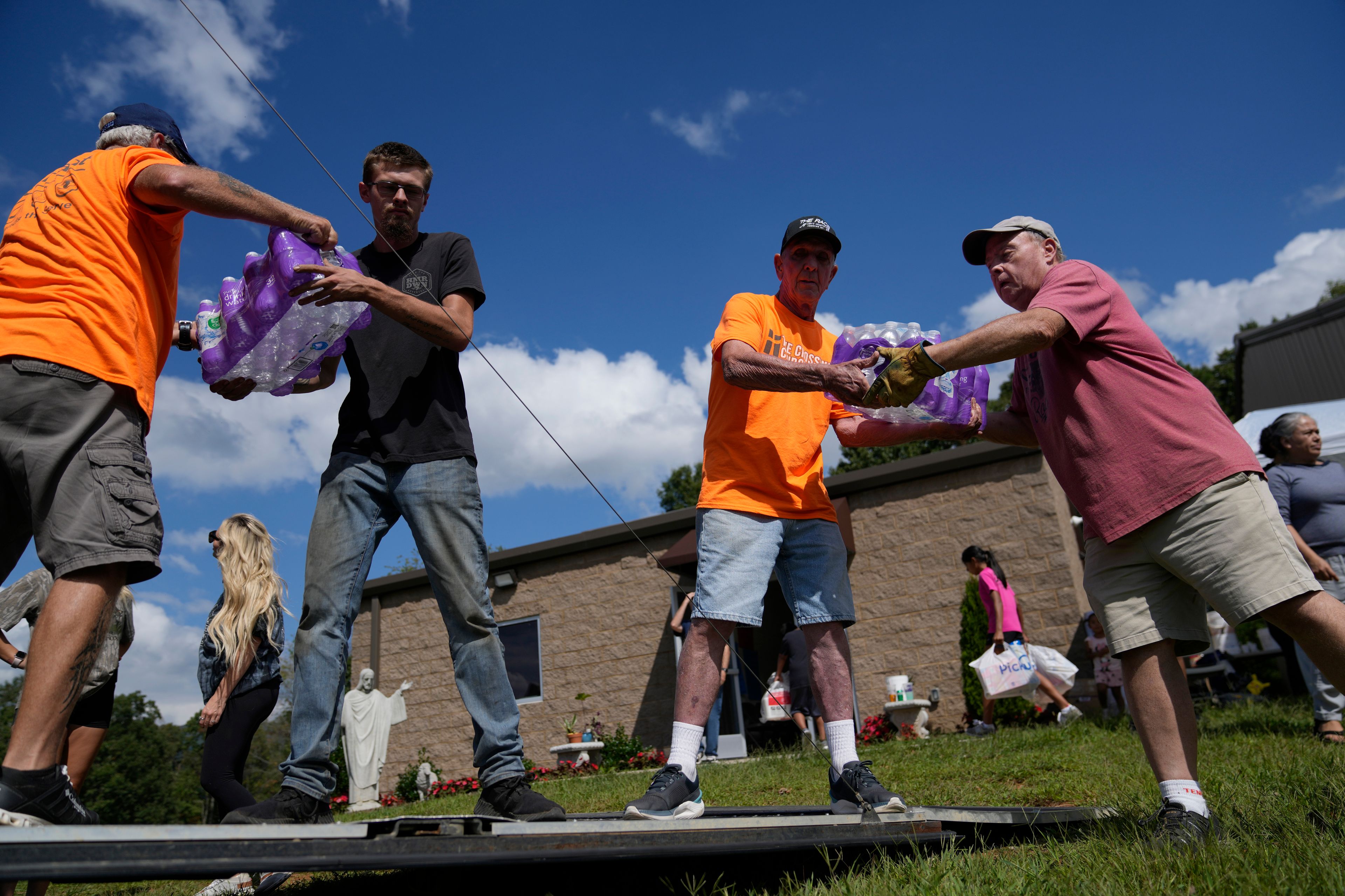 Volunteers unload cases of water and other donated supplies outside St. Michael the Archangel Catholic church in the aftermath of Hurricane Helene in Erwin, Tenn., on Thursday, Oct. 3, 2024. (AP Photo/Jeff Roberson)