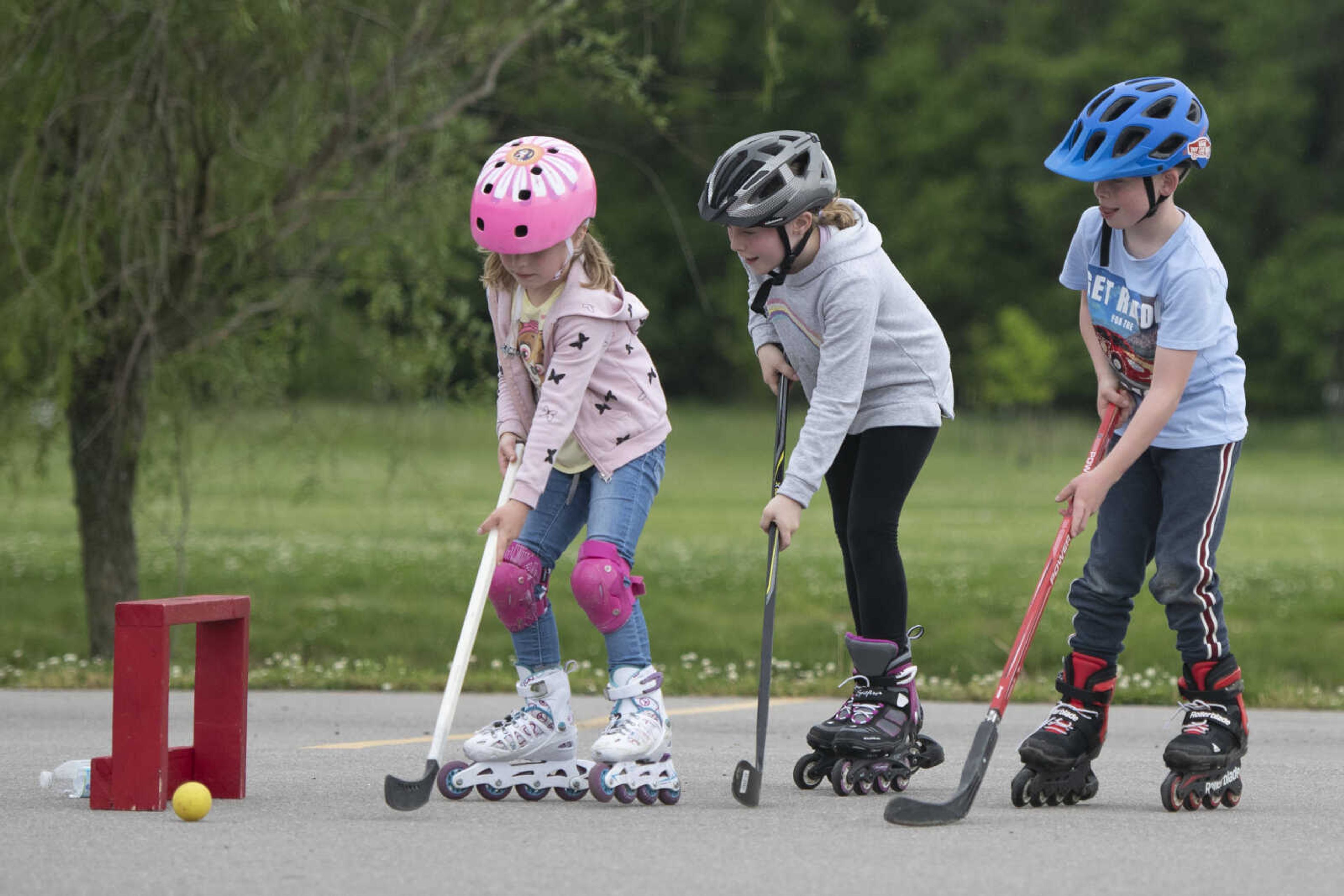 Booch siblings of Cape Girardeau, from left, Matilda, 5, Emma, 9, and Henri, 7, play hockey Wednesday, May 20, 2020, at a parking lot near Cape Splash Family Aquatic Center in Cape Girardeau.