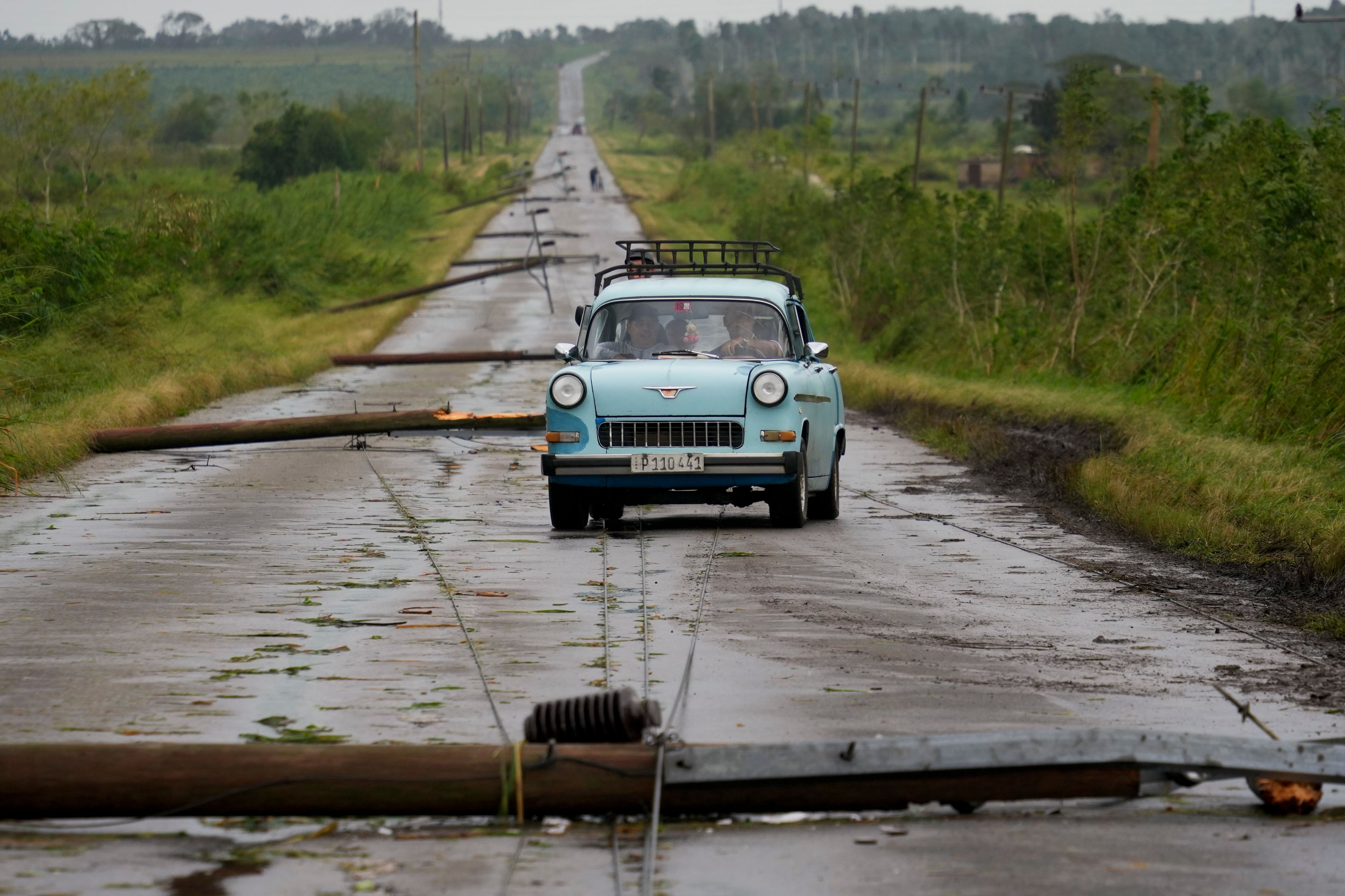 People drive along a road littered with fallen power lines after the passing of Hurricane Rafael in San Antonio de los Banos, Cuba, Thursday, Nov. 7, 2024. (AP Photo/Ramon Espinosa)