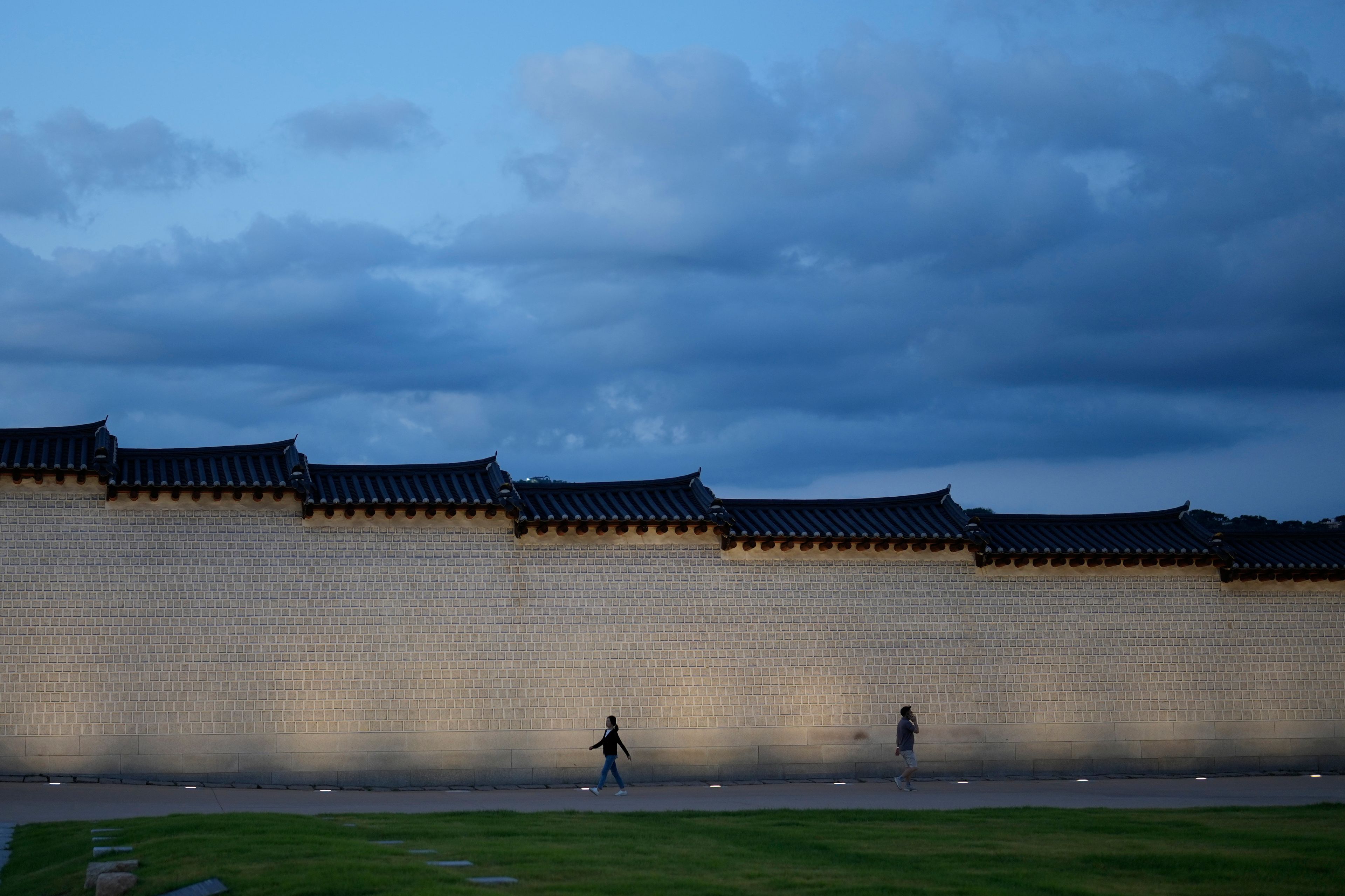 People walk along a wall outside the Gwanghwamun, one of South Korea's well-known landmarks, in downtown Seoul, South Korea, Friday, Sept. 27, 2024. (AP Photo/Lee Jin-man)