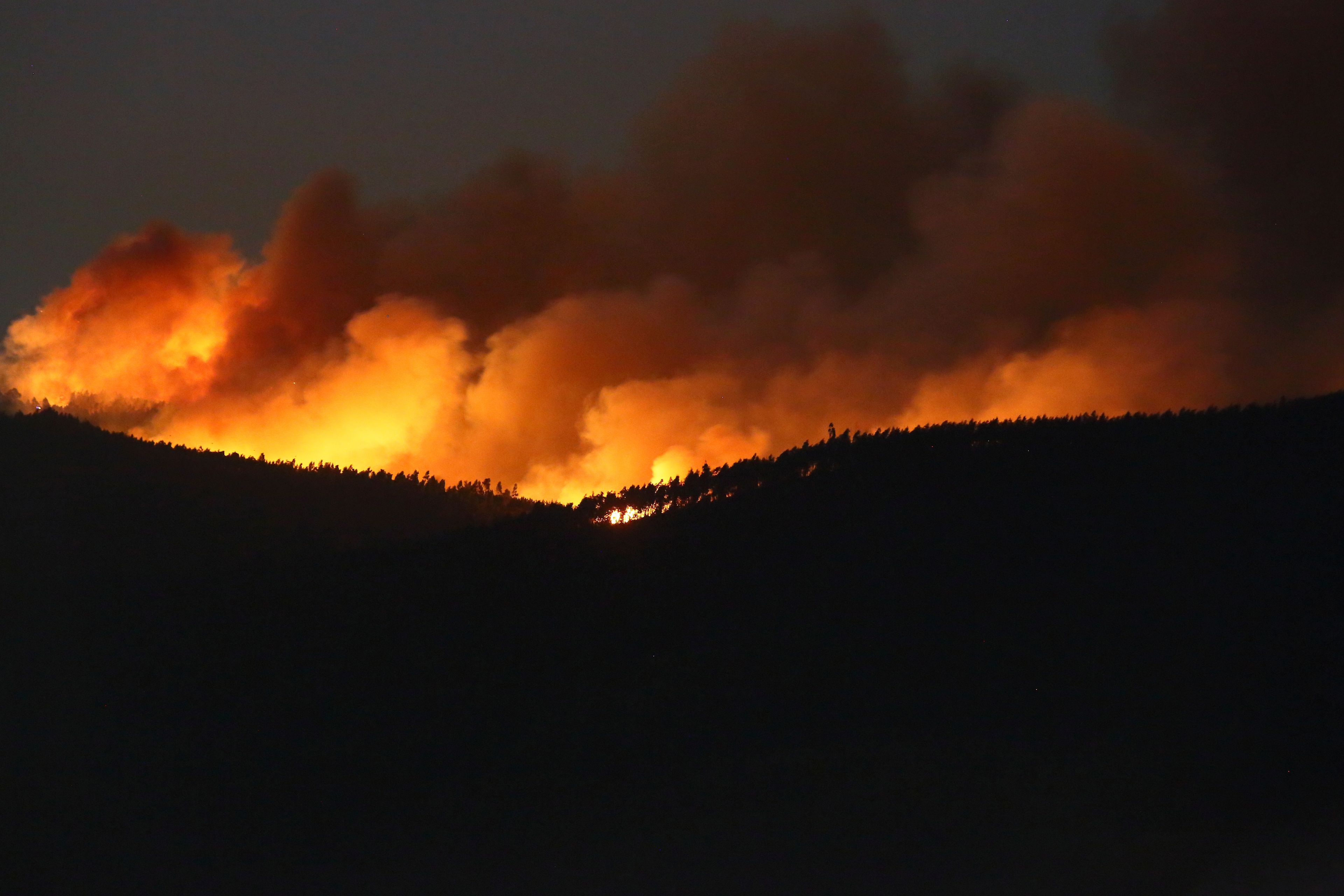 A fire rages on the hills around Sever do Vouga, a town in northern Portugal that has been surrounded by forest fires, Tuesday night, Sept. 17, 2024. (AP Photo/Bruno Fonseca)